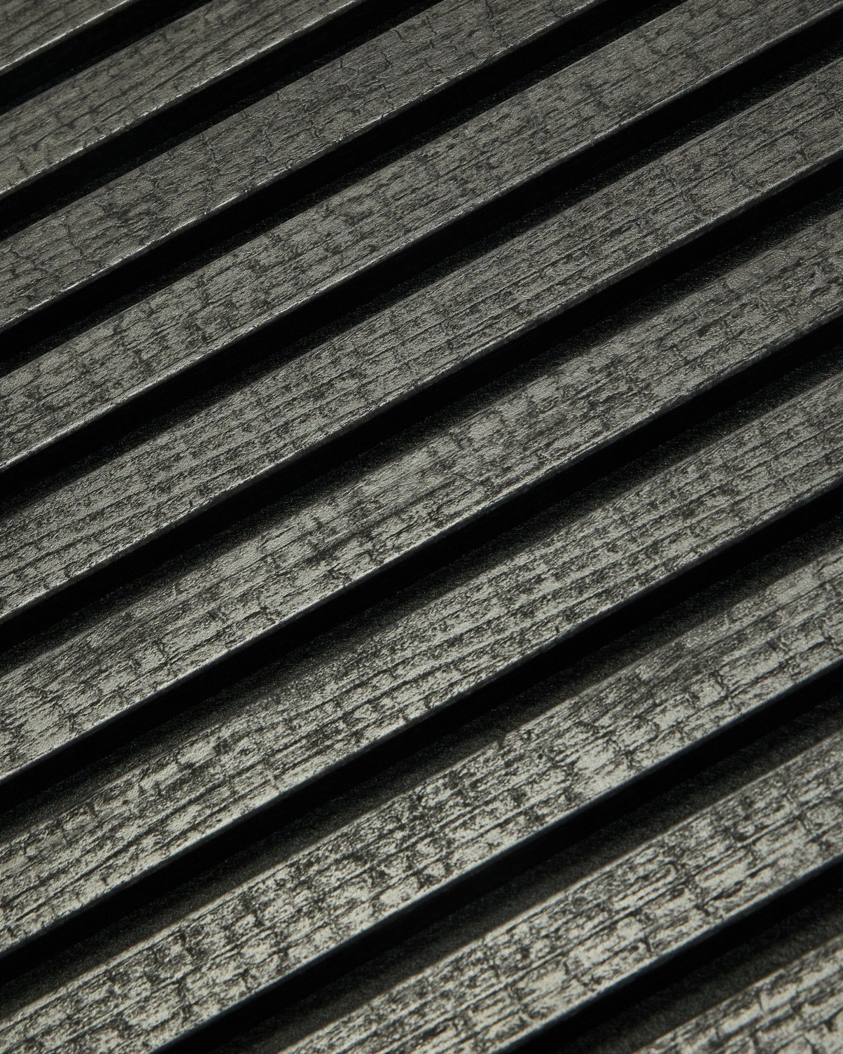Nærbillede af WoodUpp Rebel Akupanel i Charcoal (240x60 cm), som viser black, rillede akustiklameller arrangeret diagonalt for forbedret lydabsorption.