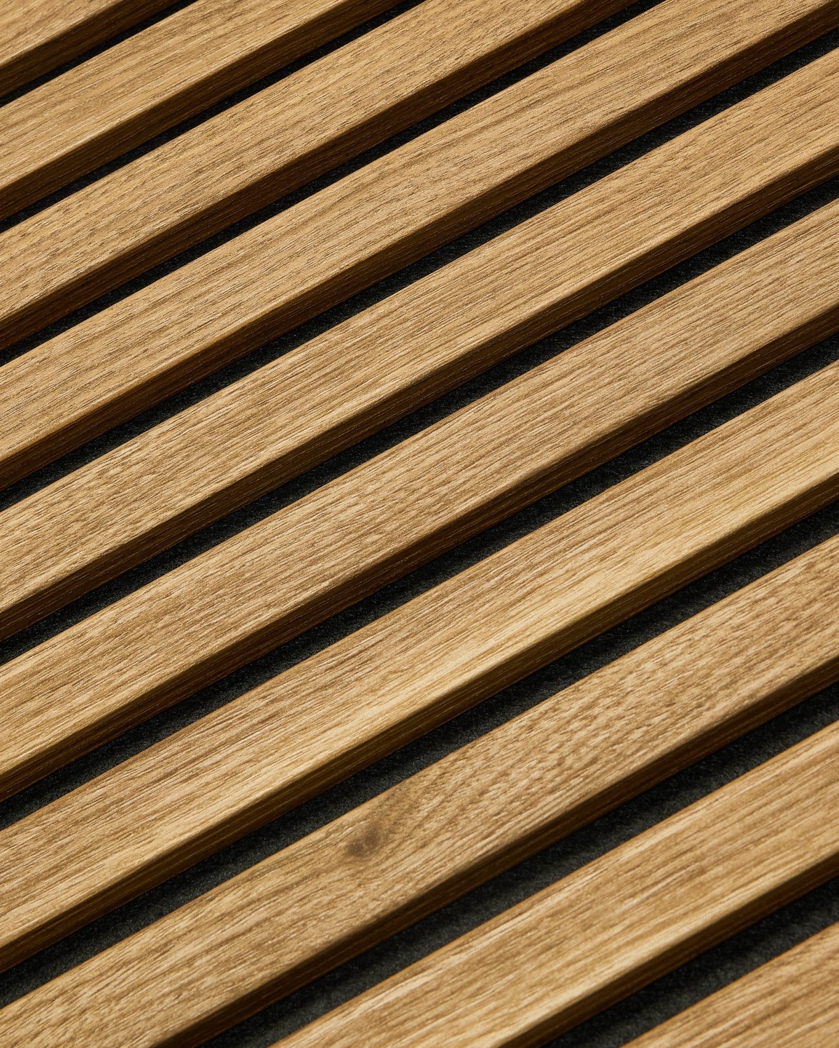 Essential Akupanel Akustikpanel i English Oak fra WoodUpp, 240 x 60 cm, med jævnt fordelte diagonale lameller på en mørk baggrund.