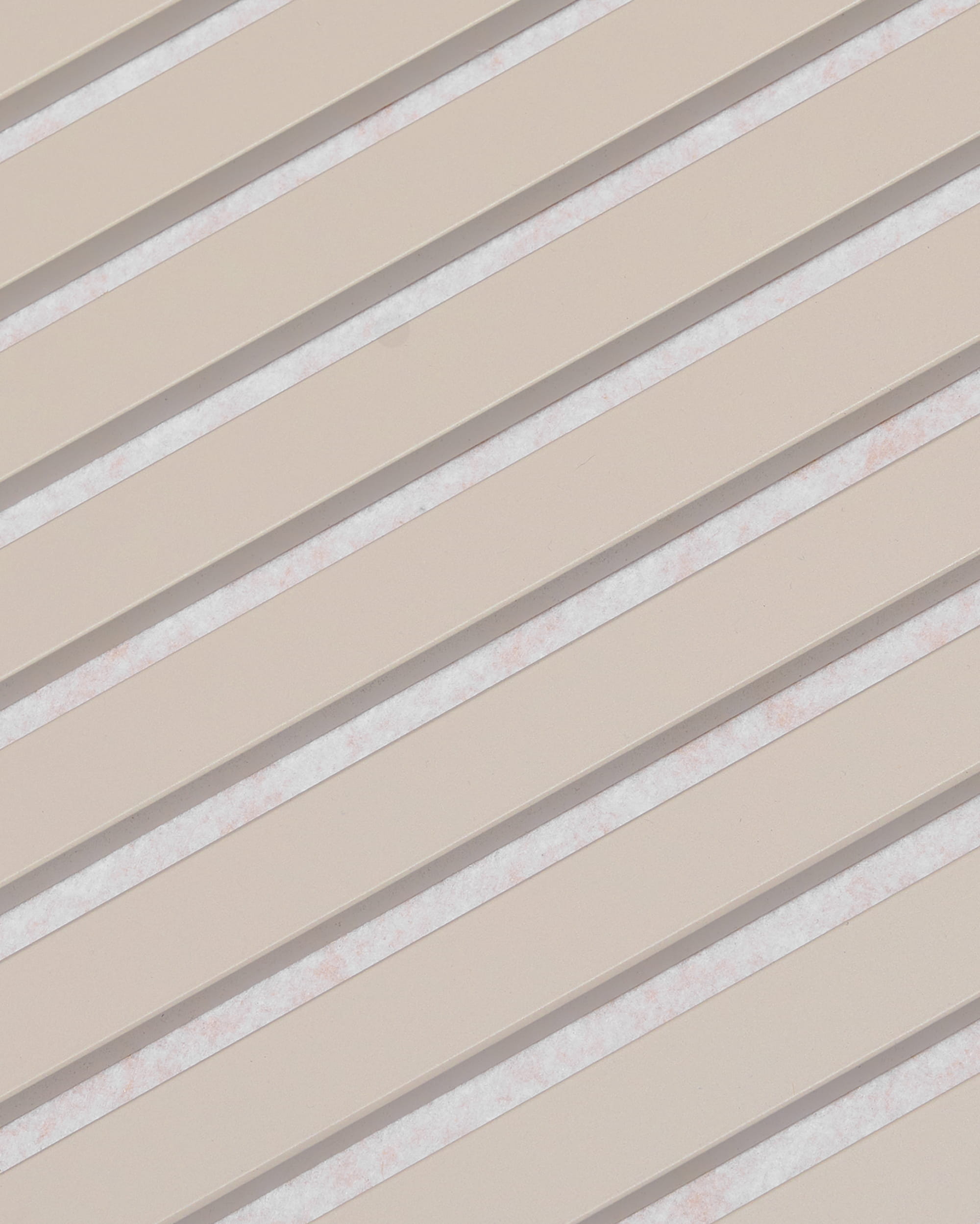 Diagonale beige lameller med hvide mellemrum danner et stribet mønster på WoodUpp Akupanel-akustikpanelet med overfladen »Soft Linen Light Beige Felt«, 240 x 60 cm.