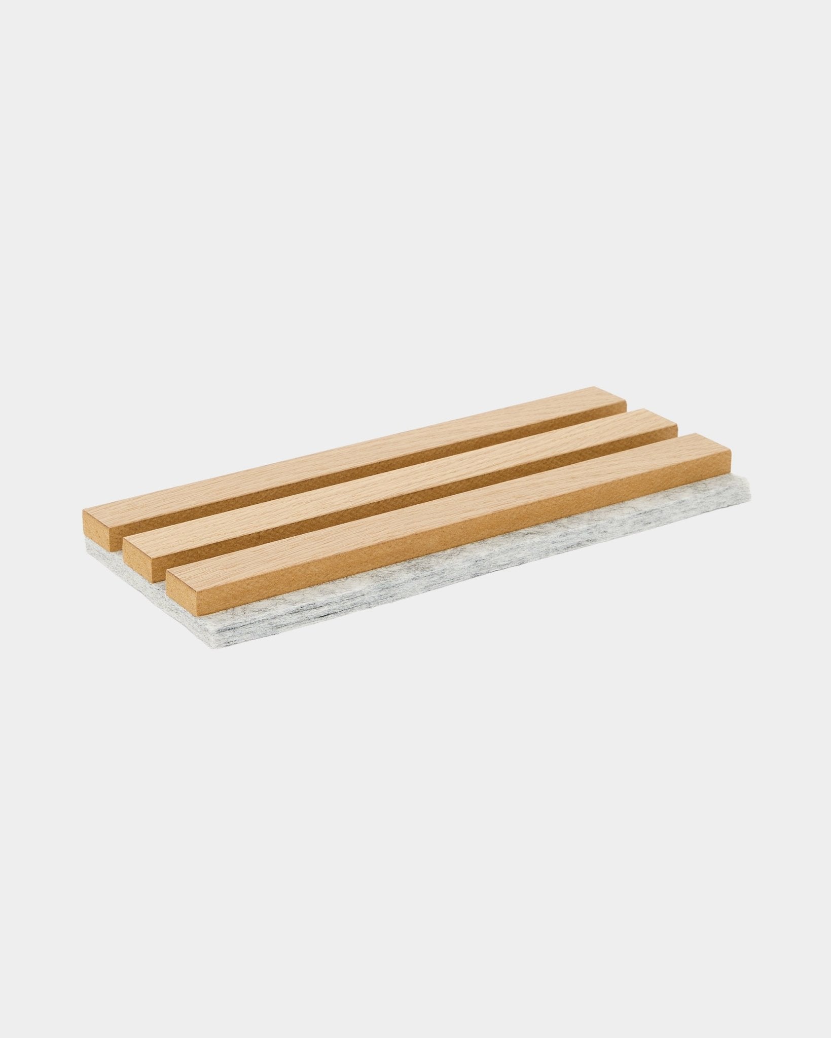WoodUpp Akupanel sample trivet featuring classic oak slats with a gray felt backing, designed to protect surfaces and showcase Nordic acoustic material.