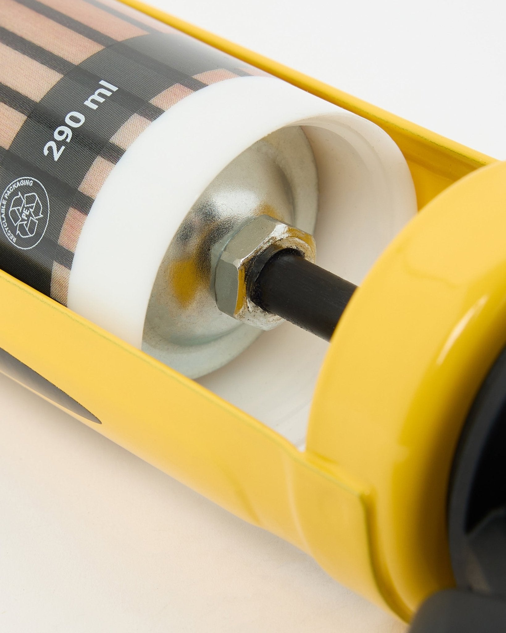 Detailed view of the WoodUpp Grout Gun (290 ml), a yellow installation tool with metal components used for mounting acoustic panels and room dividers.