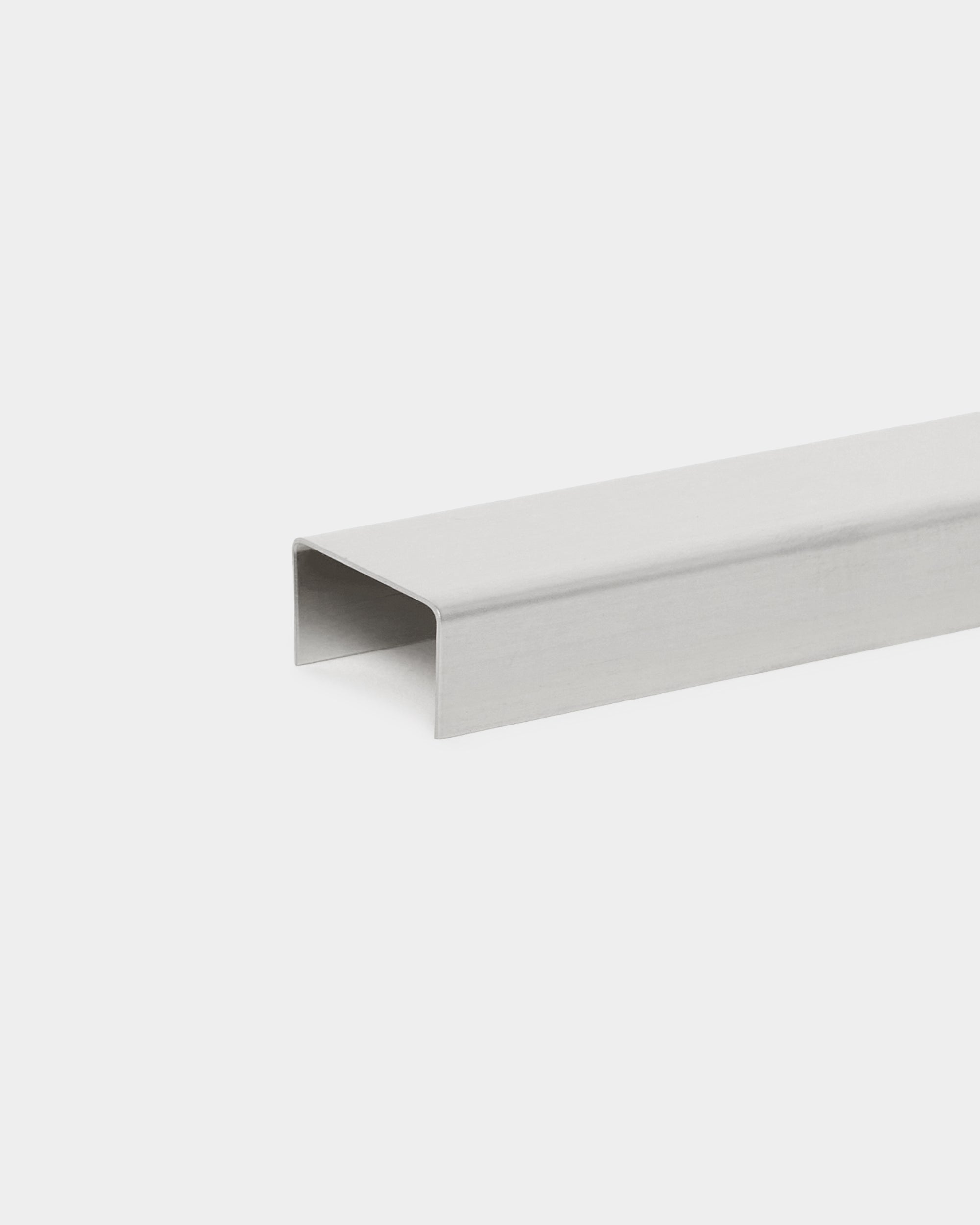 Liva Cover fra WoodUpp: 60 cm poleret steel U-formet metalkanaltilbehør, designet til brug med Akupanel akustikpaneler, vist på en hvid baggrund.