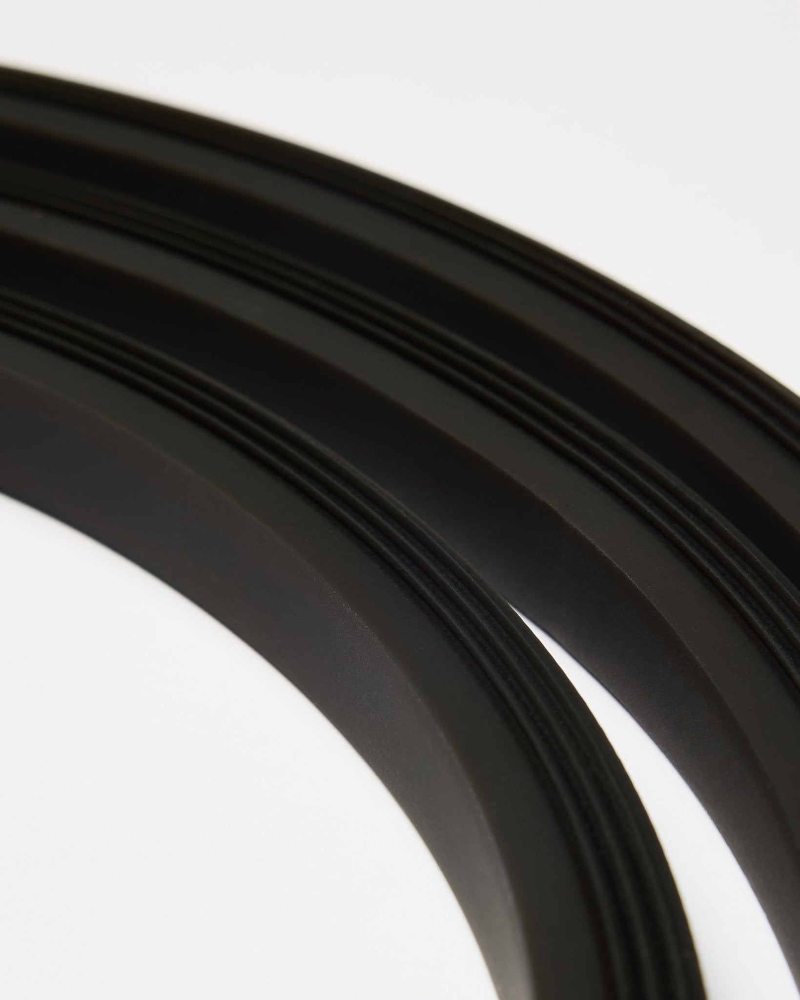 Nærbillede af black Lumi LED-lysbåndet fra WoodUpp (300 cm), arrangeret i buede linjer på hvid baggrund, som passer til den minimalistiske Akupanel Akustikpanel stil.