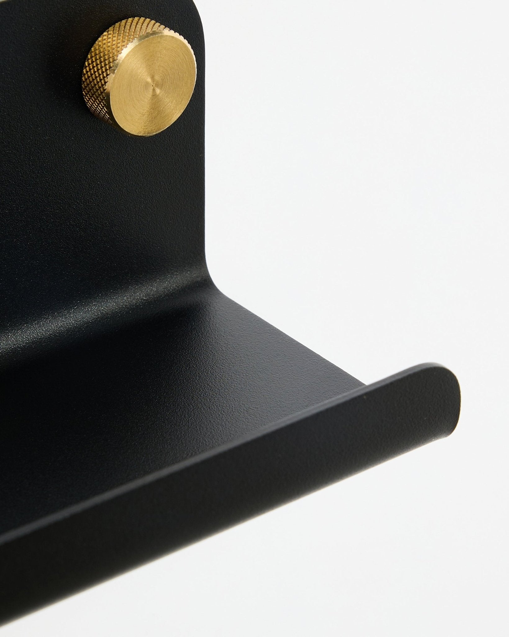 Nærbillede af WoodUpp Norr Smal hylde i black, 75,9 cm, med en tekstureret guldknop, vist mod en hvid baggrund.