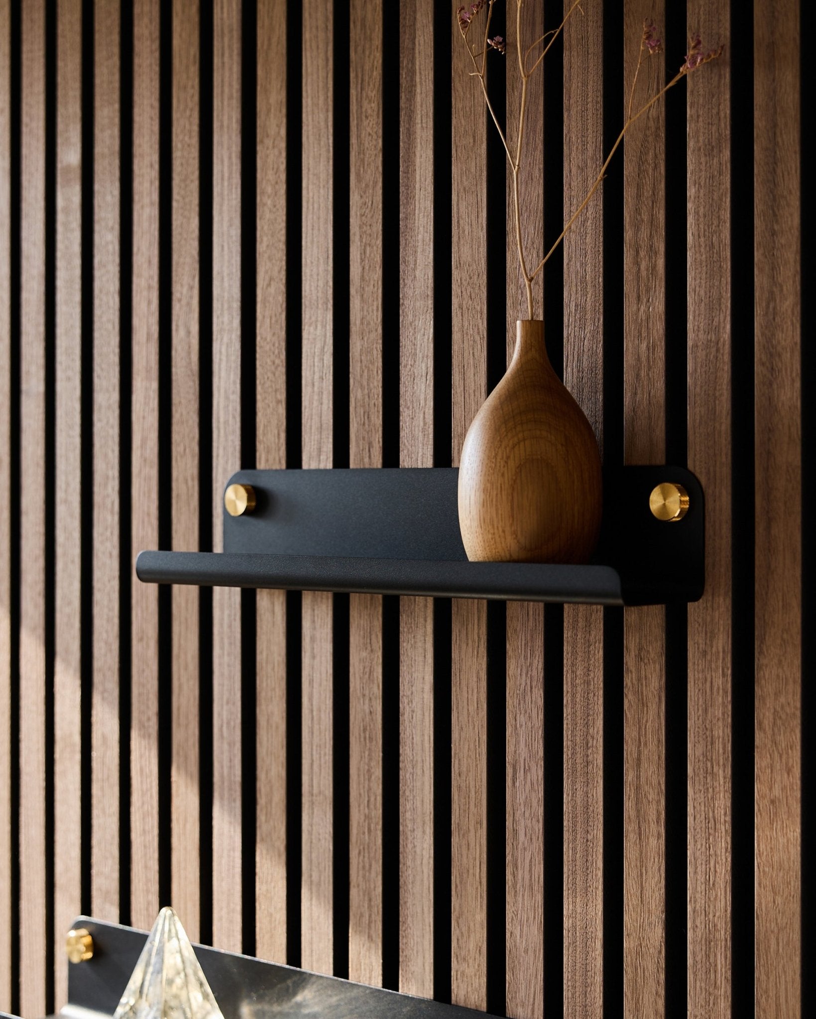 En trævase med tørrede grene på en black WoodUpp Norr smal hylde (35,9 cm), sat op mod et vertical akustikpanel med lameller i nordisk stil.