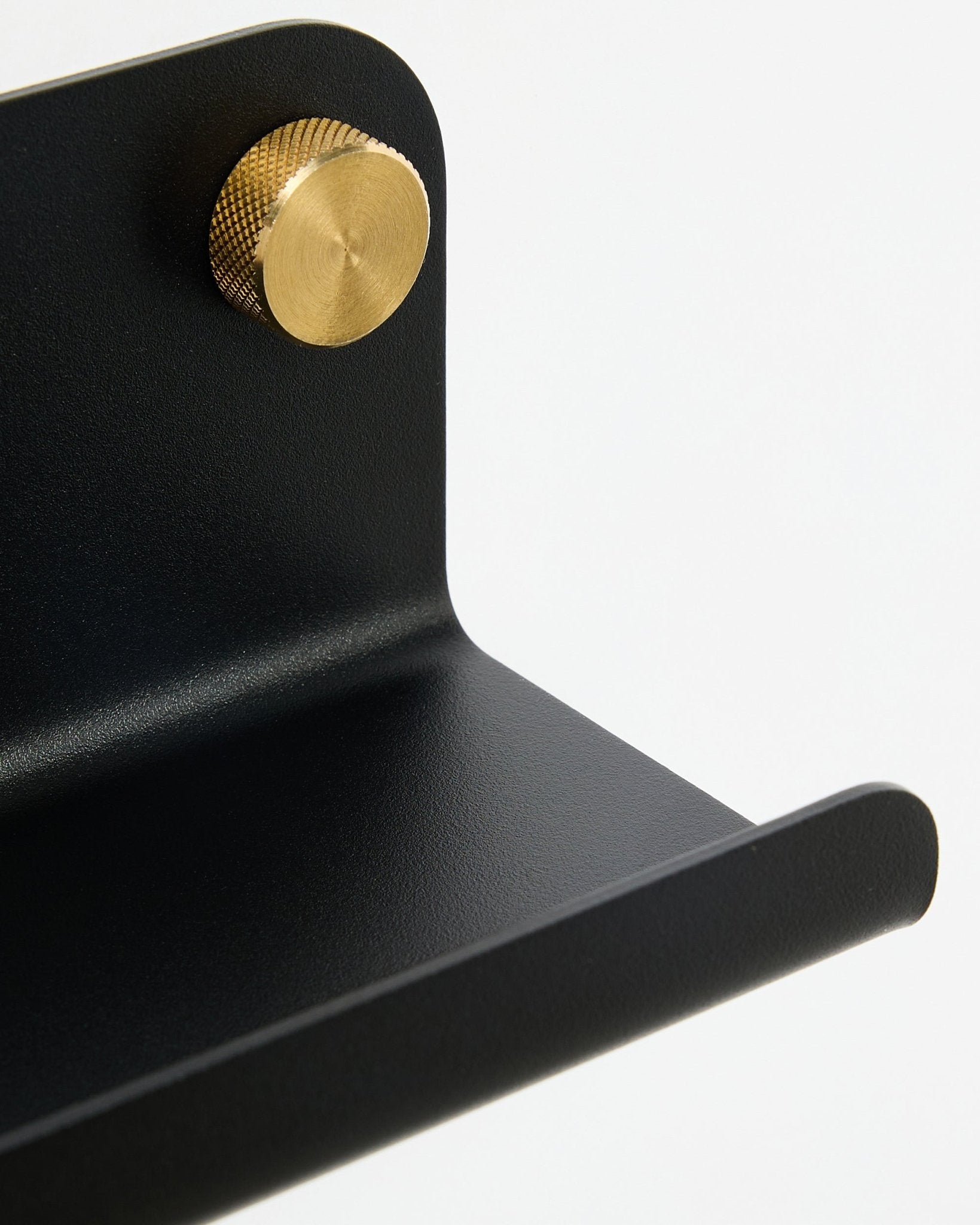 Nærbillede af WoodUpp Norr smal hylde, 35,9 cm, black steel med buet kant og guldfarvet knop, vist mod en hvid baggrund.