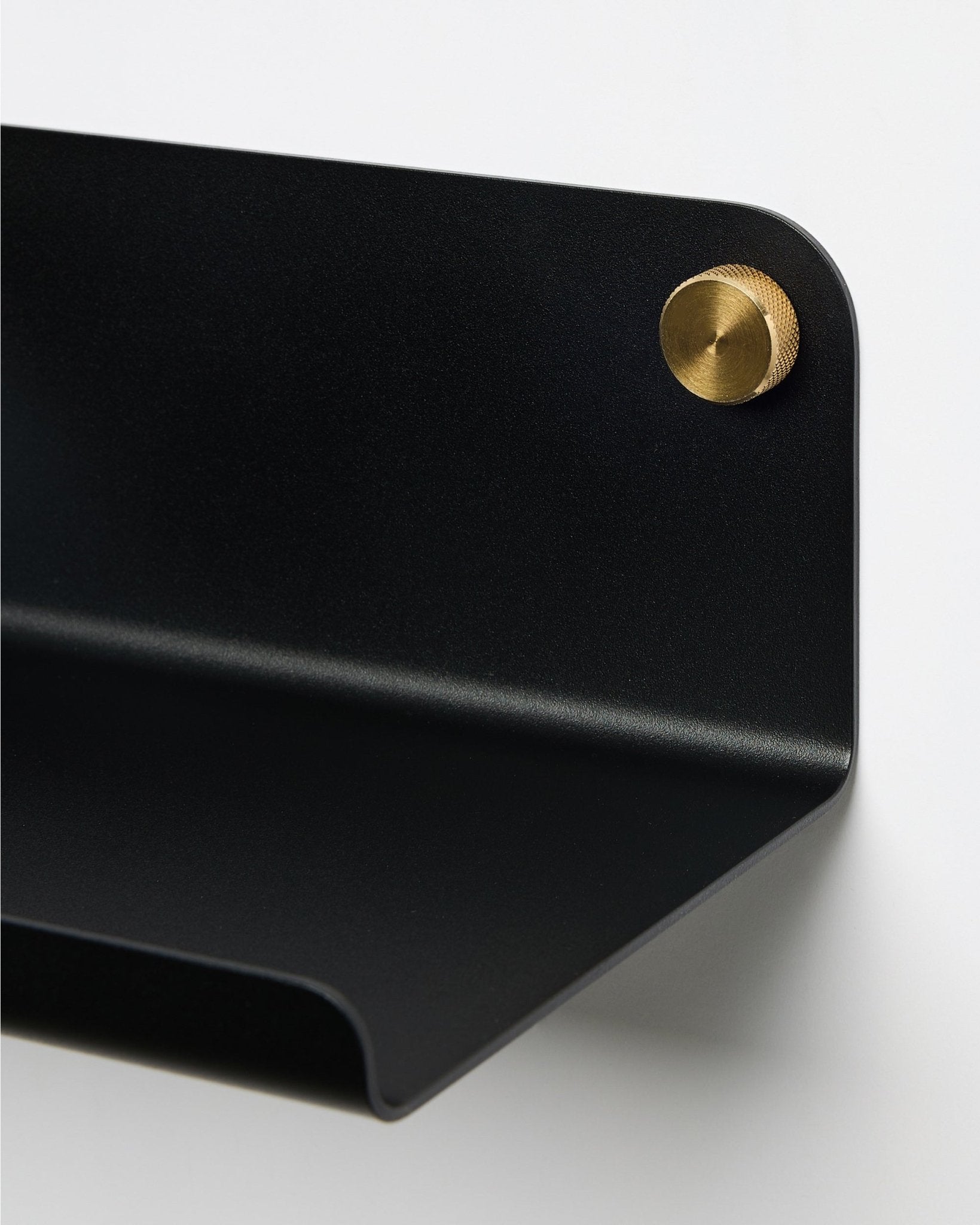 Nærbillede af WoodUpp Norr brede hylde i black, 35,9 cm, med en afrundet kant, monteret på væggen med en rund brass skrue. Nordisk minimalistisk design.