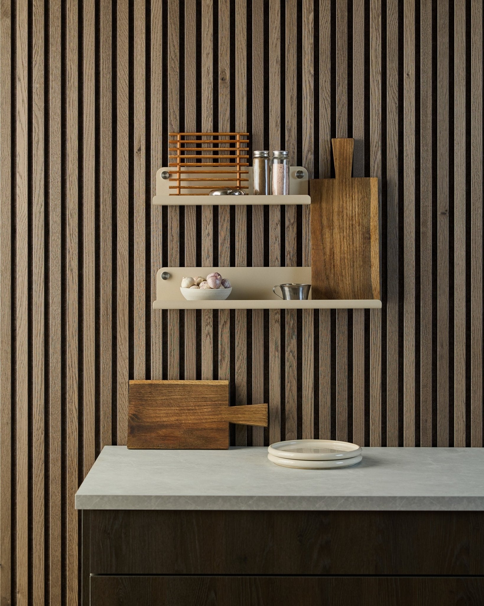 Minimalist kitchen with Nordic Akupanel wooden acoustic slat wall, open shelves holding spices and bowls, countertop with white plates and a cutting board.