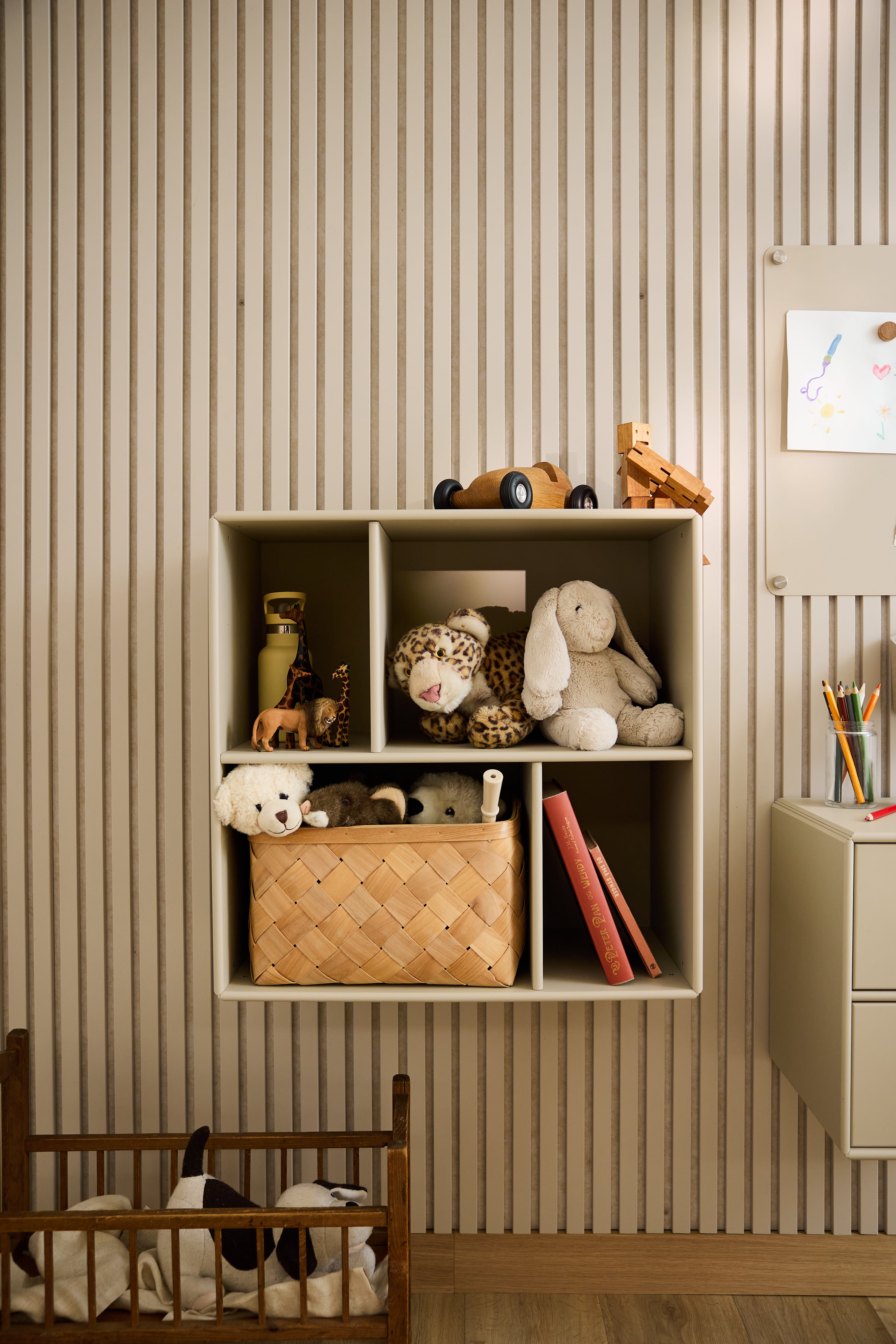 WoodUpp Arka-vitrineskab i beige med legetøj og bøger, der står foran det stribede tapet i et børneværelse, er et eksempel på minimalistisk nordisk design.