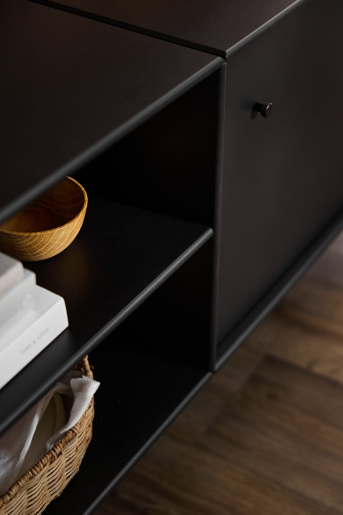Sort Arka TV-kommode fra WoodUpp med minimalistisk design, udviklet til kabelføring og opbevaring, placeret på et trægulv.