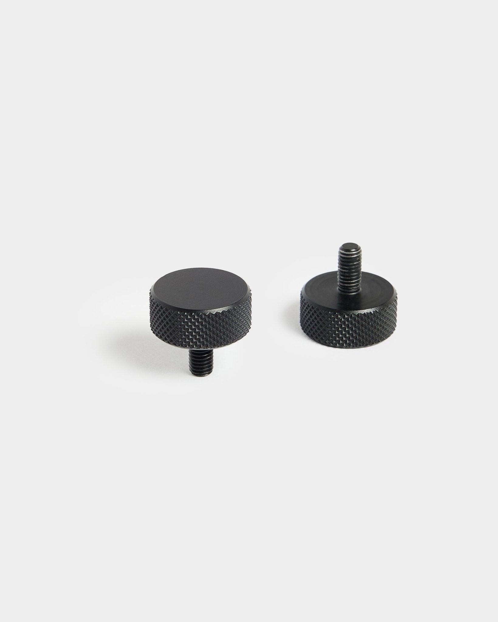 Et par black WoodUpp Finger-skruer (M5x10 mm, 20x8.8) med riflede kanter, designet til brug med Akustikpanel tilbehør, på en enkel hvid baggrund.