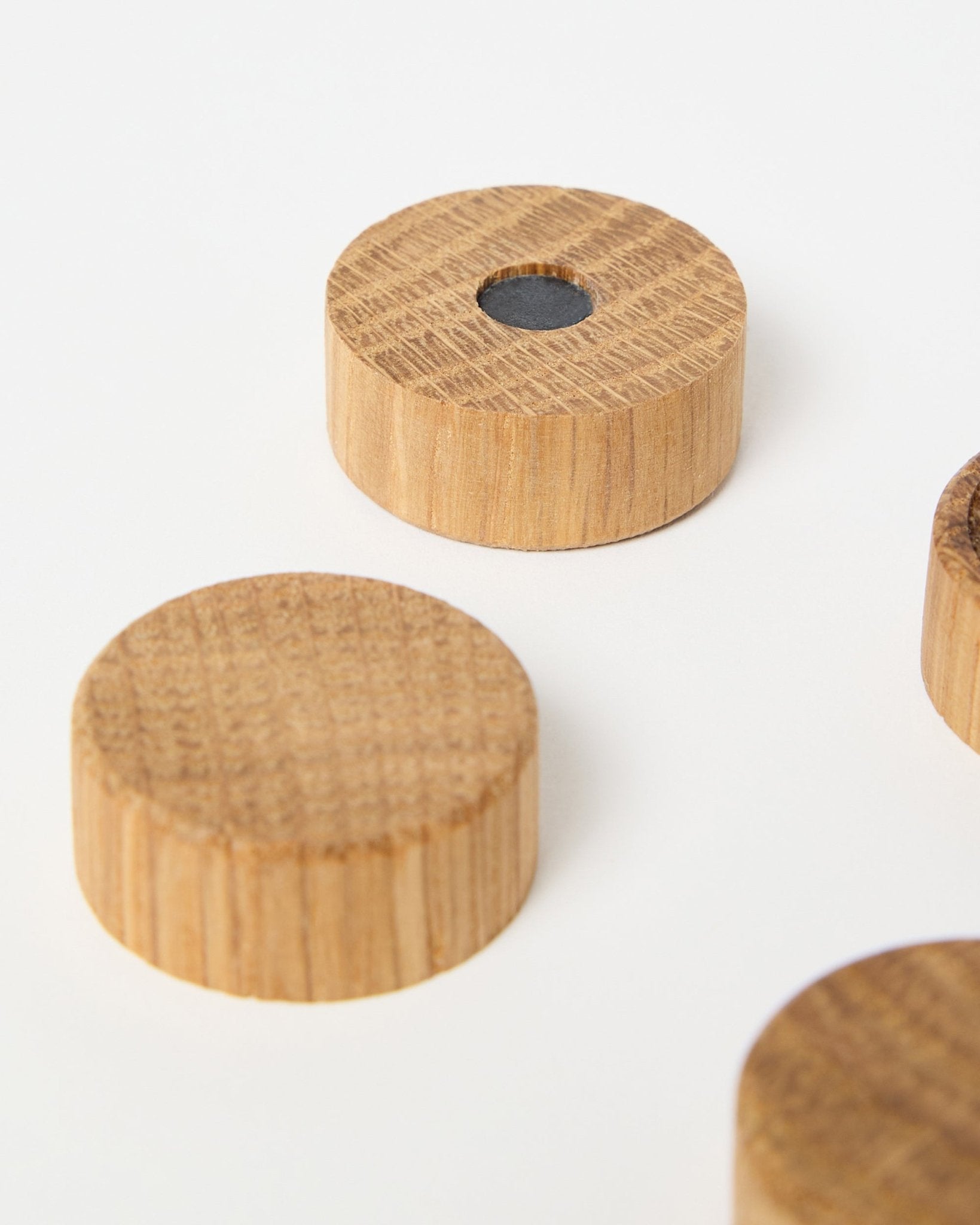Sæt med fire natural oak magneter fra WoodUpp, designet til brug med Akupanel akustikpaneler i træ, hvor én har en central neodymmagnet for ekstra greb, vist på hvid baggrund.