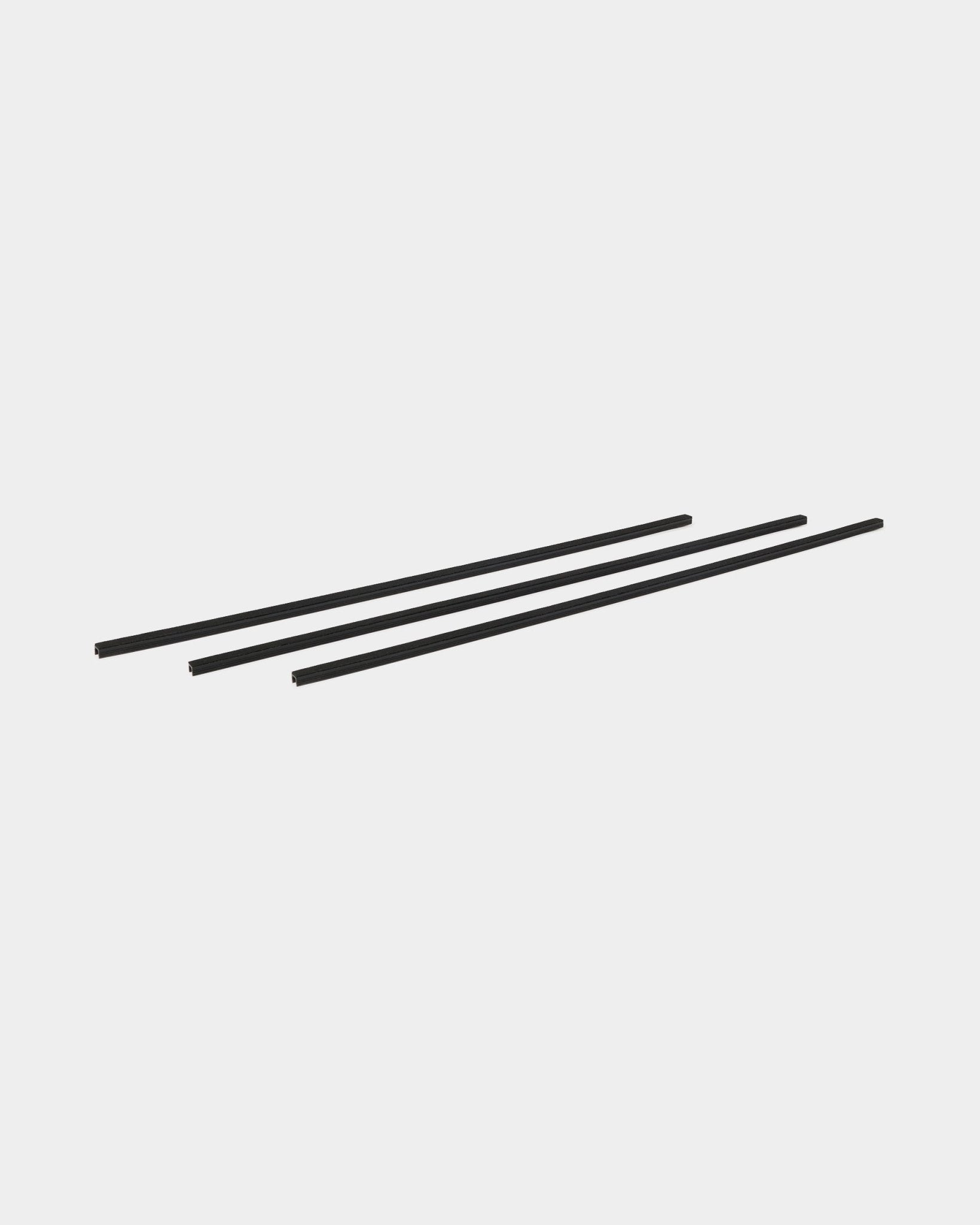 Three black Dupps Pop-on Cable Covers (set of 3) by WoodUpp, designed as accessories for Akupanel, arranged diagonally on a plain white background.