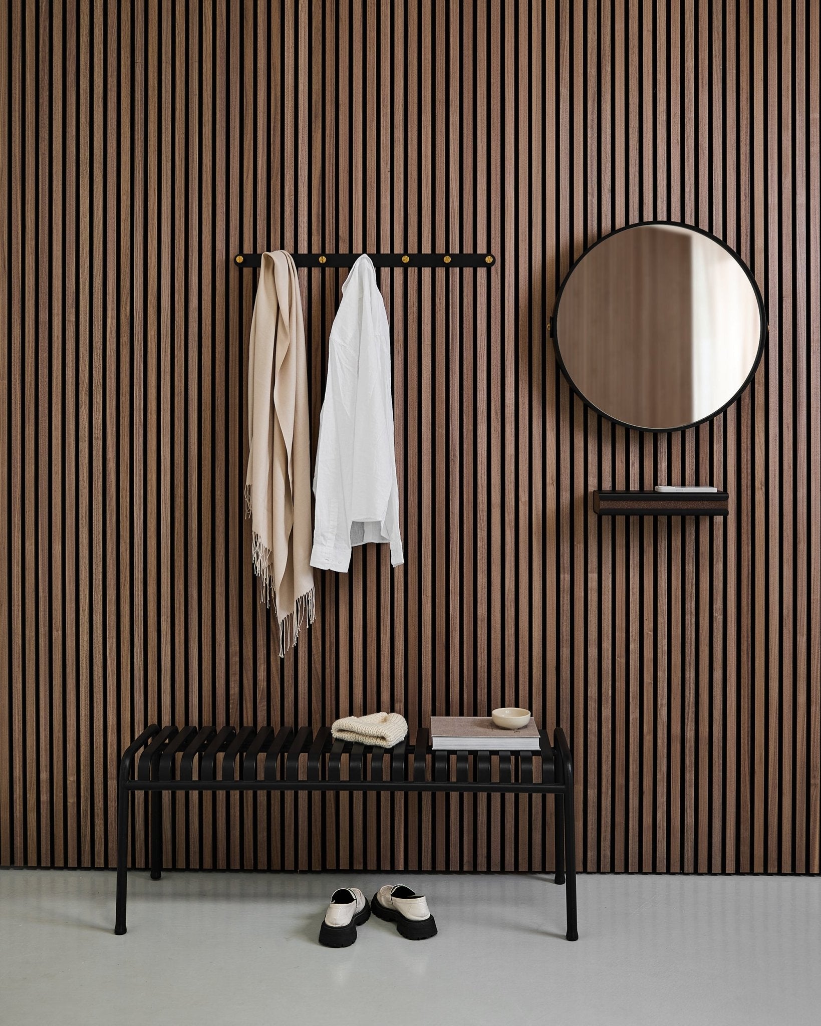 Minimalist entryway with a WoodUpp Linn | Mirror in Black Oak, Nordic acoustic slat wall panel, bench, shelf, hanging coat and scarf, and shoes on floor.