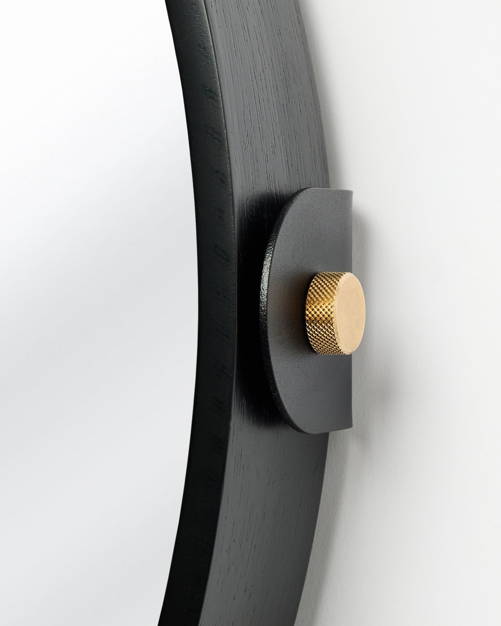 Detalje af Linn | Mirror / Black Oak Akustikpanel fra WoodUpp, monteret på væggen med en gylden knop og justerbar hældning.