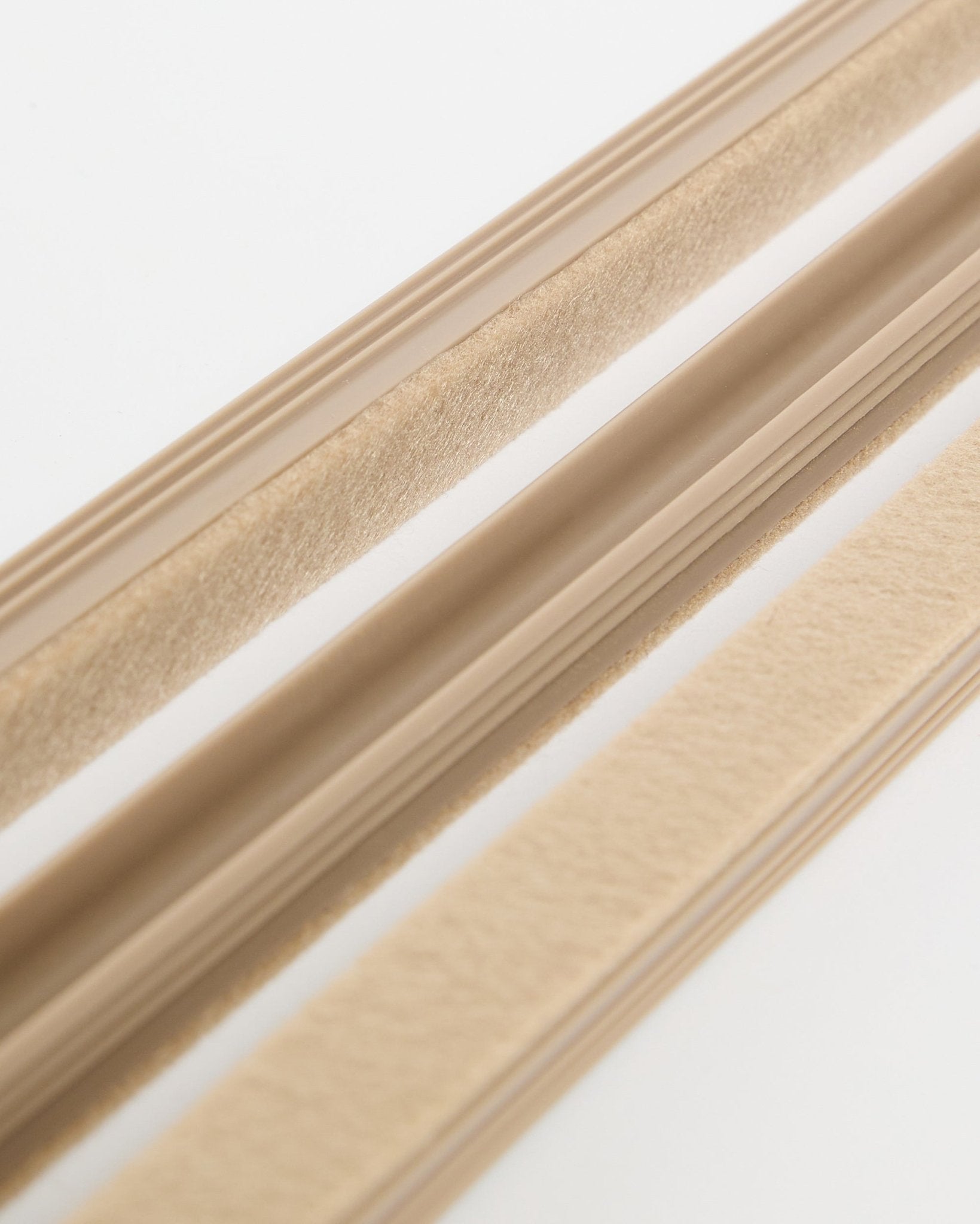 Beige WoodUpp Dupps Pop-on Cable Covers (3-pak) med filttekstur og selvklæbende bagside, vist på en hvid overflade til organisering af ledninger.