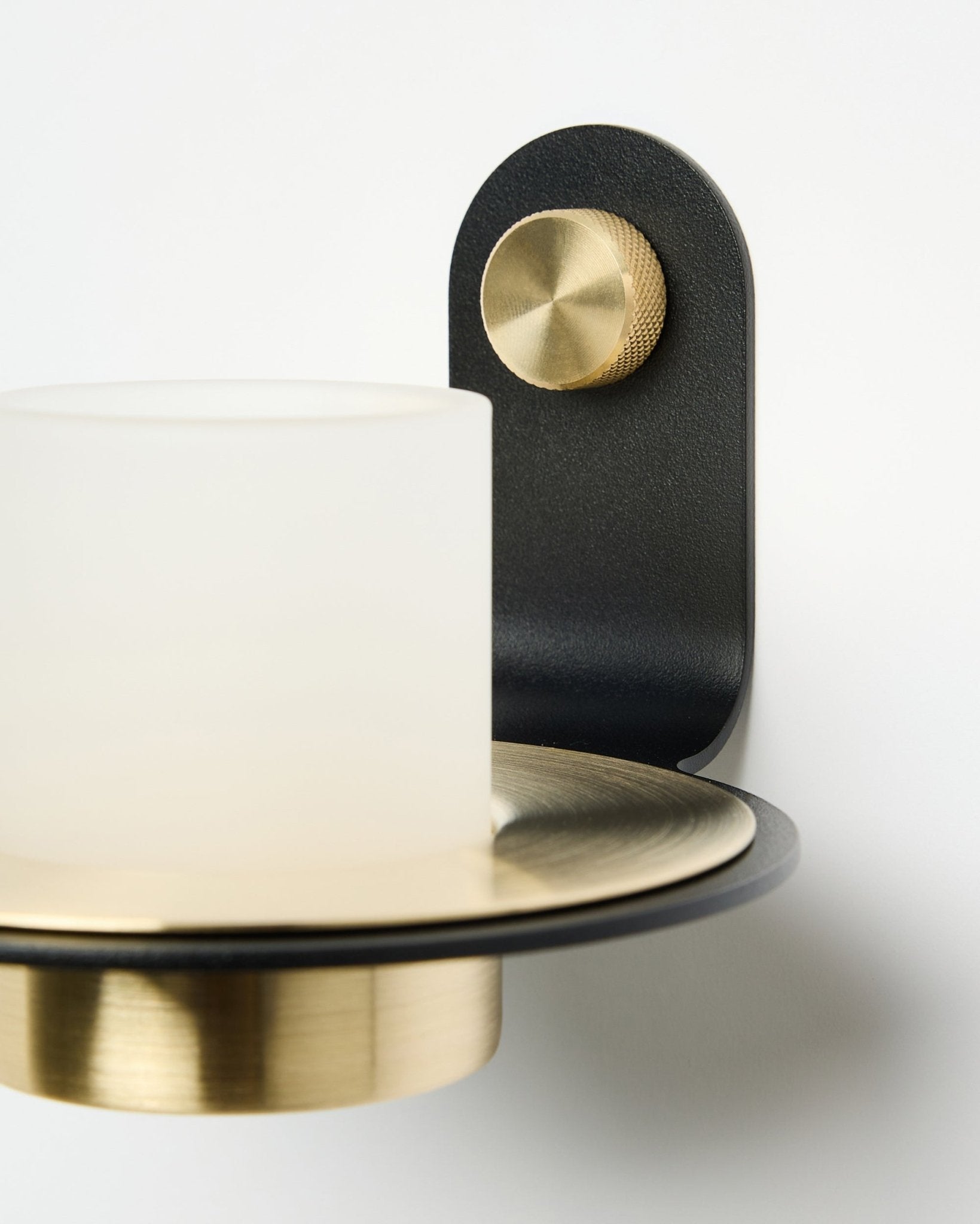 Norr lysestage fra WoodUpp i black og brass, vist monteret med LED-lys på et hvidt Akustikpanel.