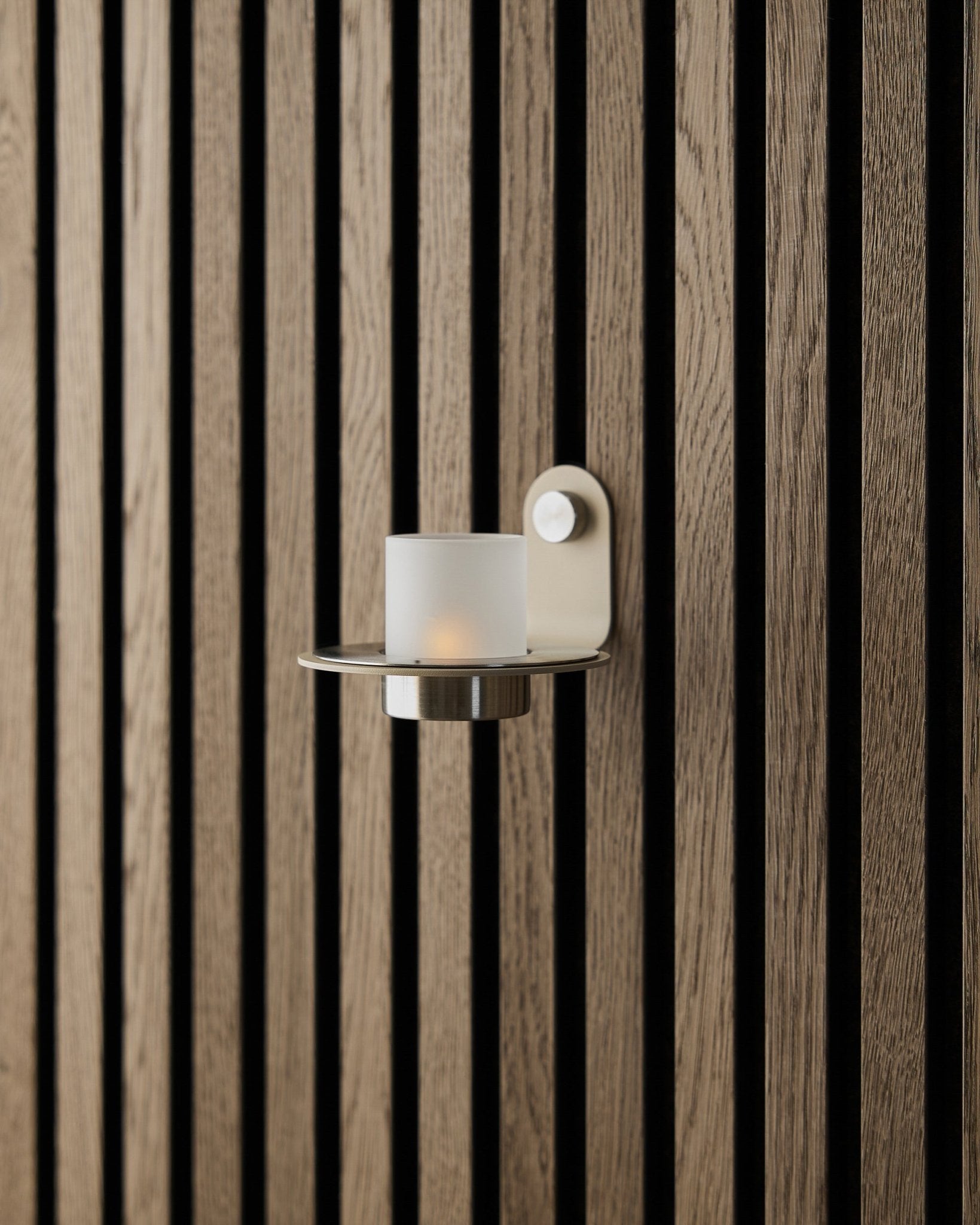 Norr lysestage i beige rustfrit steel fra WoodUpp vist på en beige Akupanel Akustikpanel væg.