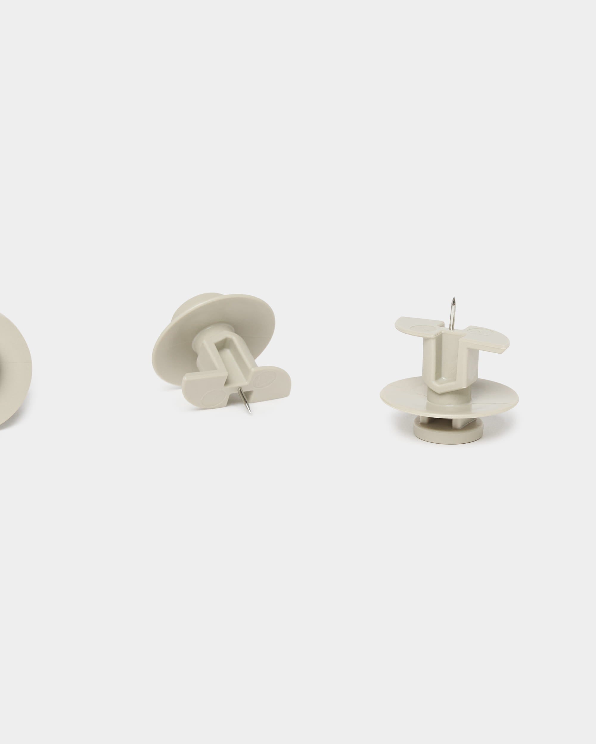 Sæt bestående af tre beige WoodUpp Dupps-stifter og et værktøj, designet til Akupanel-akustikpaneler, vist både stående og liggende på en ensfarvet hvid baggrund.