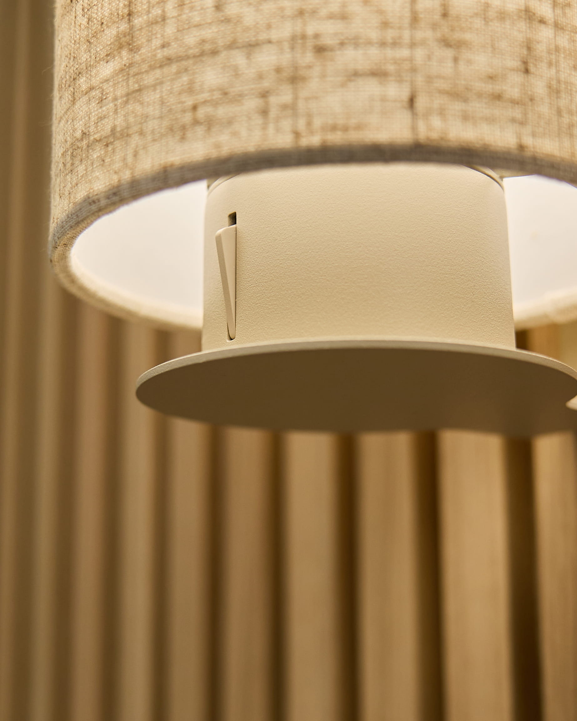 Nærbillede af Feya væglampen i Beige/Beige fra WoodUpp med en skærm i hør-bomuld og cylindrisk armatur monteret på vertical beige akustikpaneler.