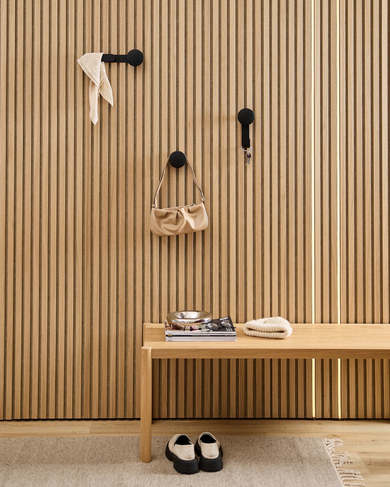 Minimalistisk entré med WoodUpp Linn Horizontal Hanger i sort eg med sorte kroge, træbænk, sko, bøger og et fad. Nordisk stil.