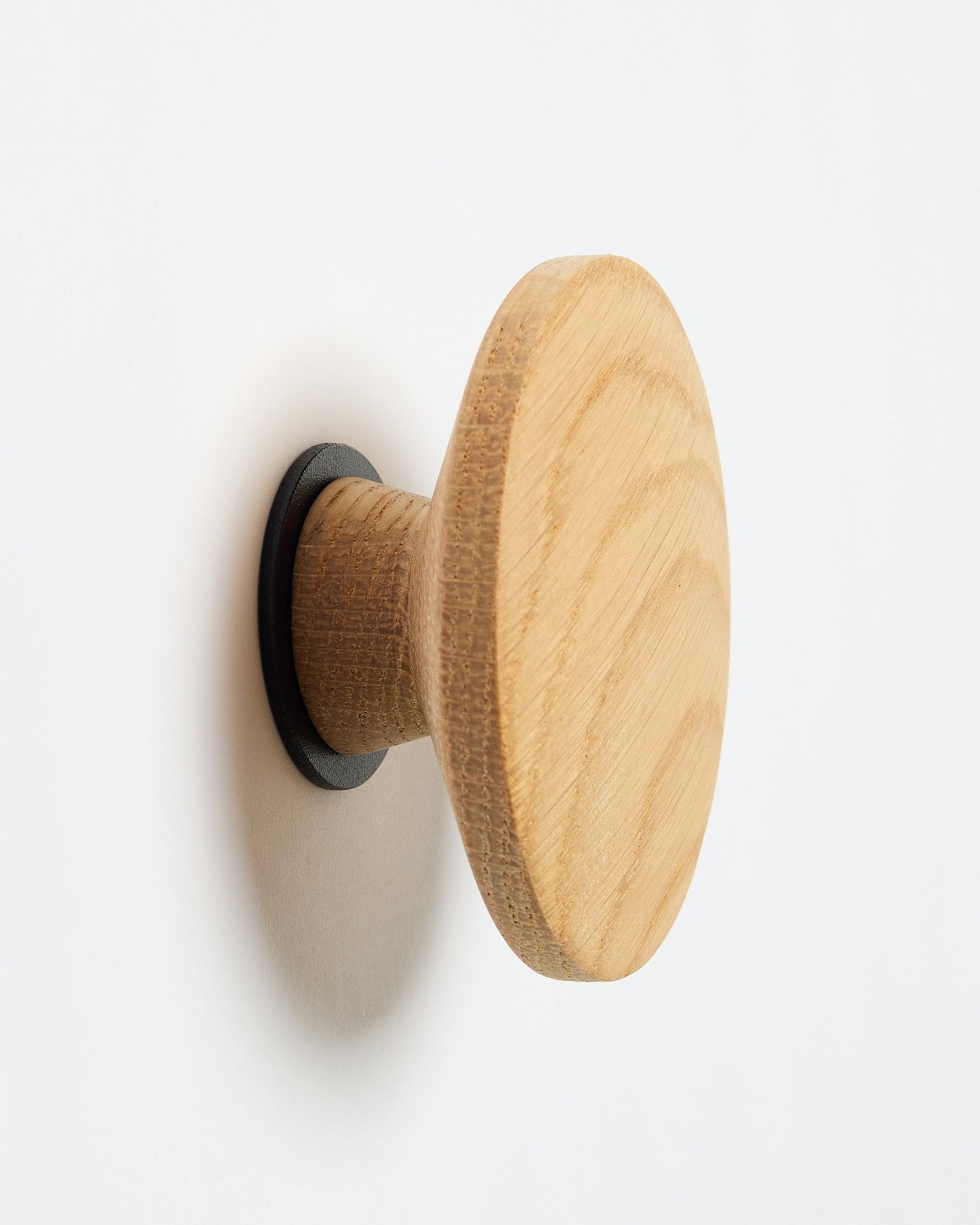WoodUpp Linn I Single Hanger i natural oak, en rund vægknage med black base, designet som tilbehør til montering på Akupanel akustikpaneler i træ.