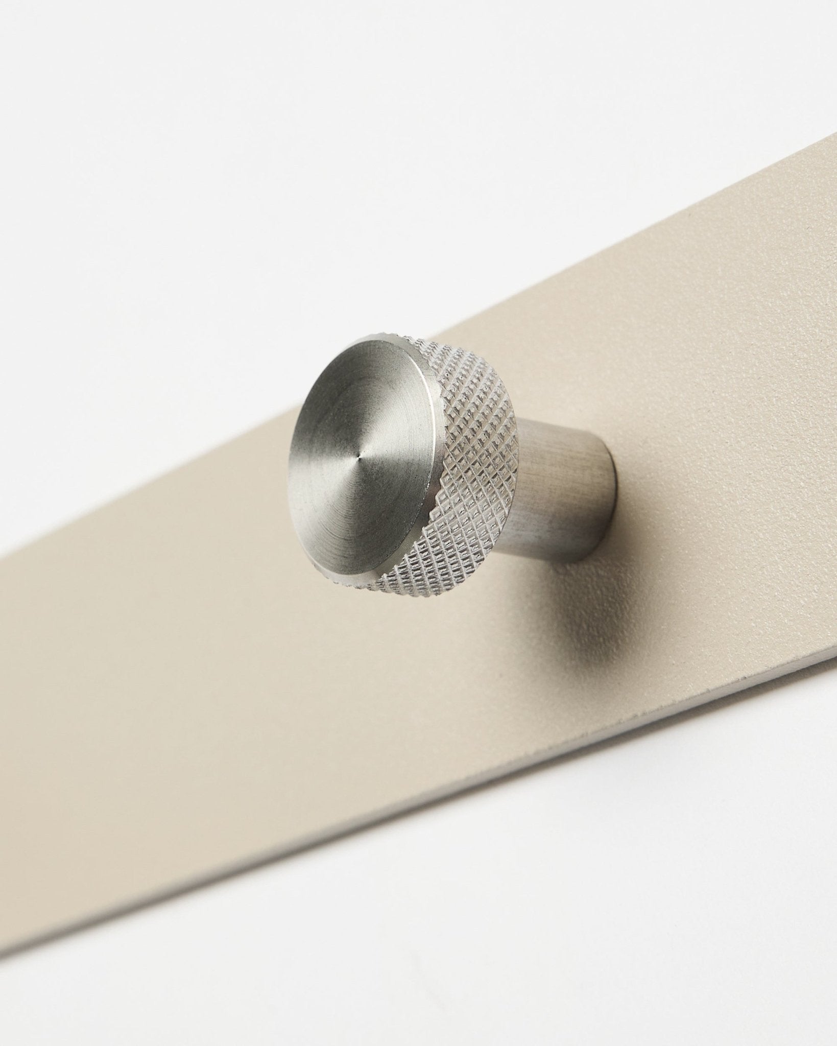 Norr knagerække i beige og rustfrit steel fra WoodUpp, tilbehør til Akupanel kollektion, vist i nærbillede mod en hvid baggrund.