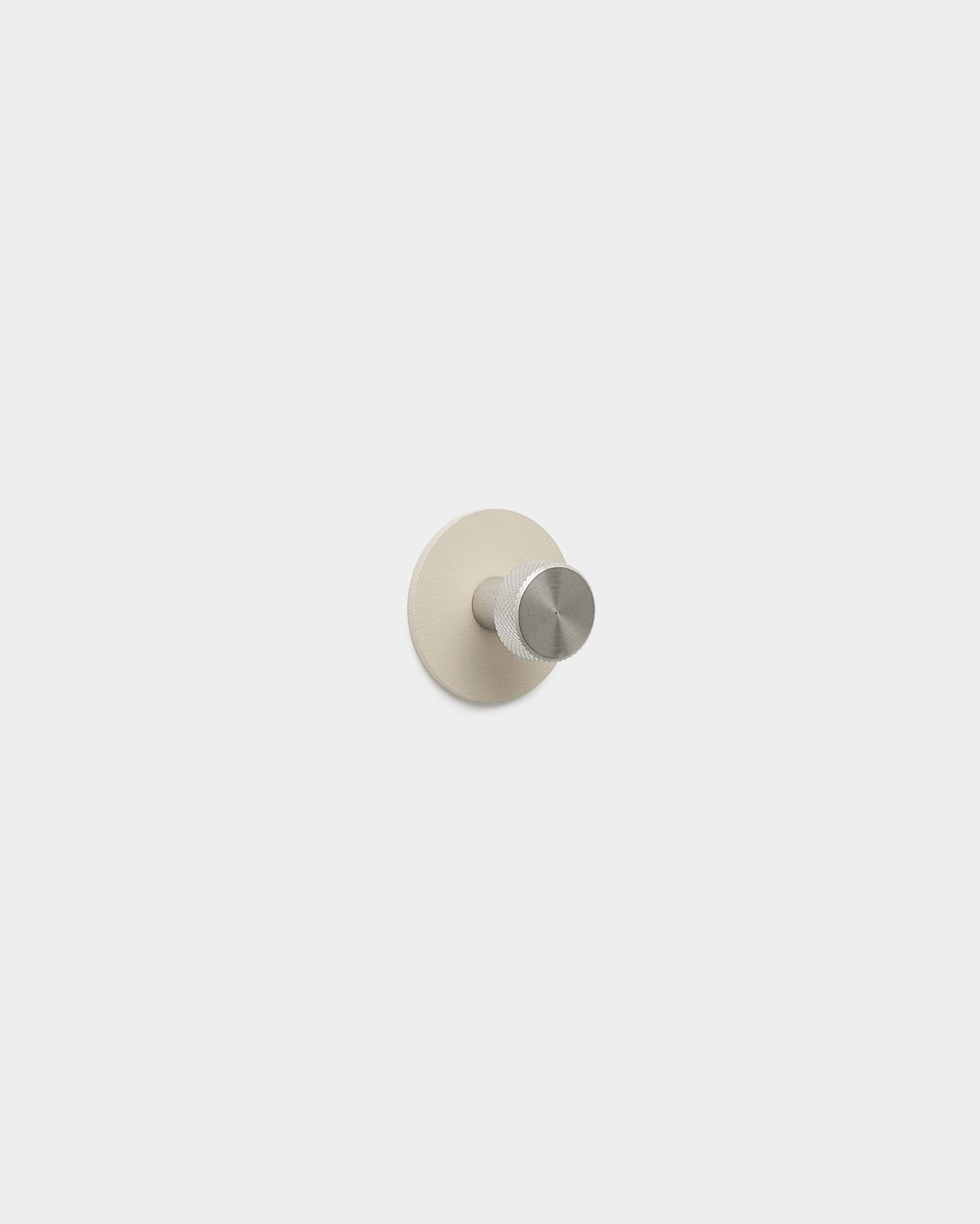 WoodUpp Norr Coat Hook i beige og rustfrit stål med en minimalistisk pind og rund base, fremstillet af pulverlakeret stål, en del af WoodUpps tilbehør.
