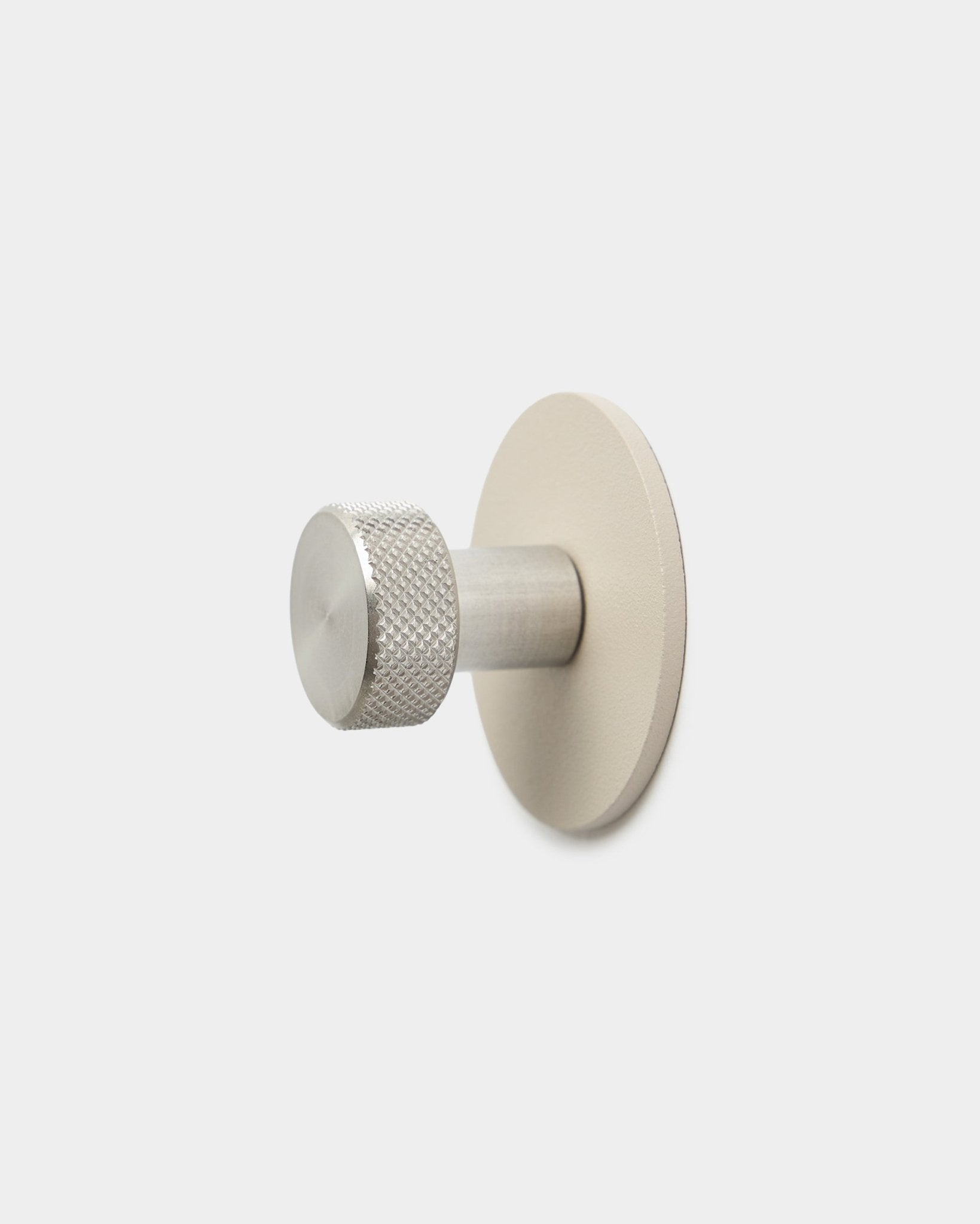 WoodUpp Norr knage i beige og rustfrit steel med en tekstureret cylindrisk ende og rund base, tilbehør til Akupanel, på en ren hvid baggrund.