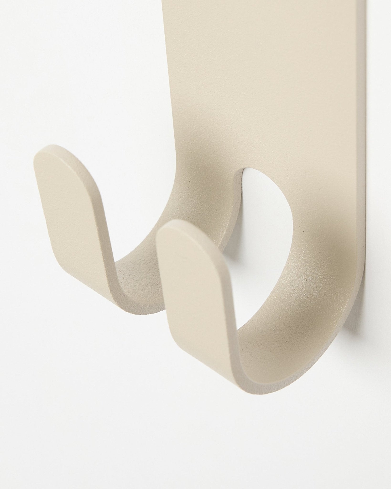 Nærbillede af Norr Double Hanger i beige fra WoodUpp, en minimalistisk metalkrog til overtøj monteret på et lyst colored Akustikpanel.