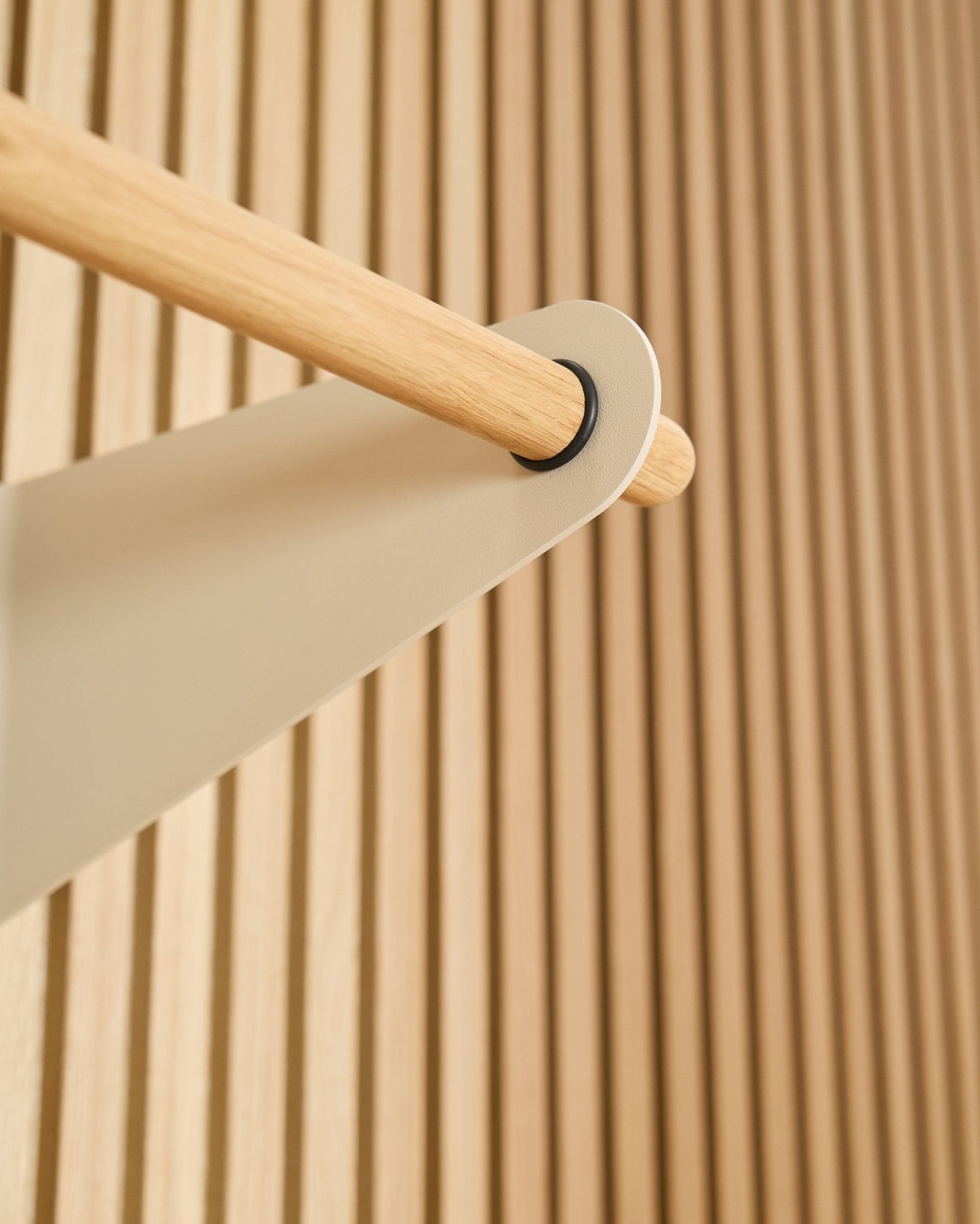 Nærbillede af WoodUpp Linn knagerække i beige (75,9 cm), monteret på et beige metalbeslag foran et tekstureret Akupanel akustisk lamelvægspanel.