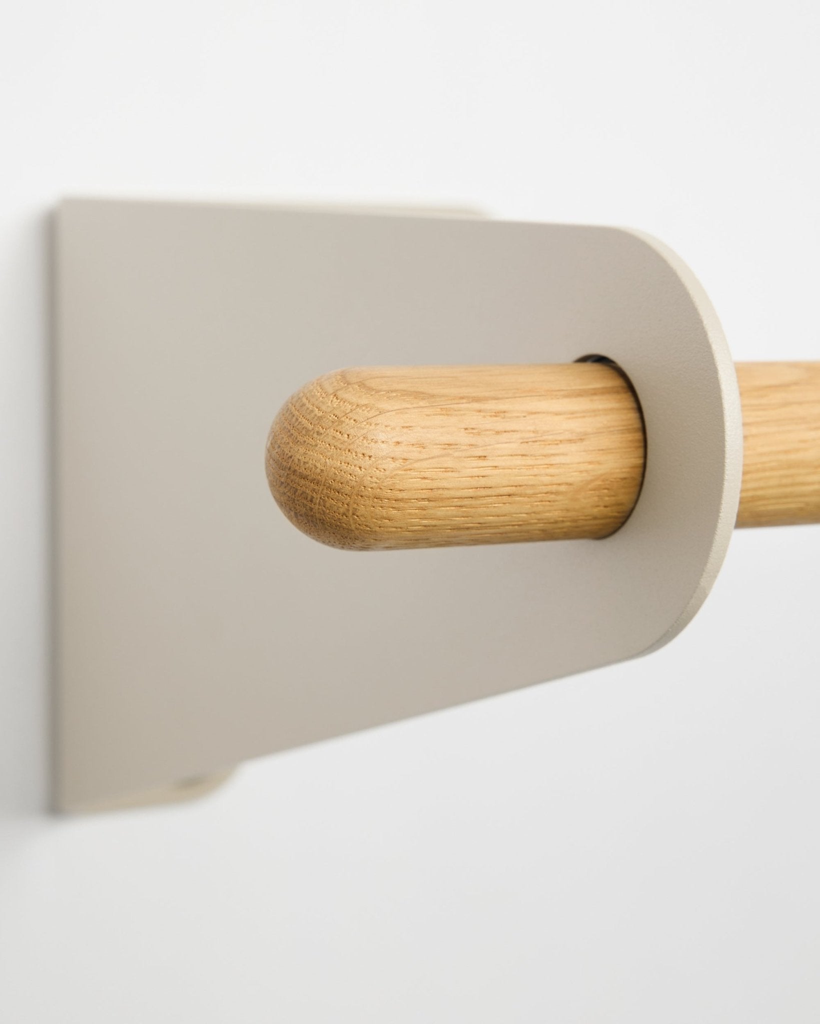 Nærbillede af WoodUpp Linn knagerække i beige, 115,9 cm, med et lyst metalbeslag i beige monteret på en hvid væg. Nordisk minimalistisk designaccessory.