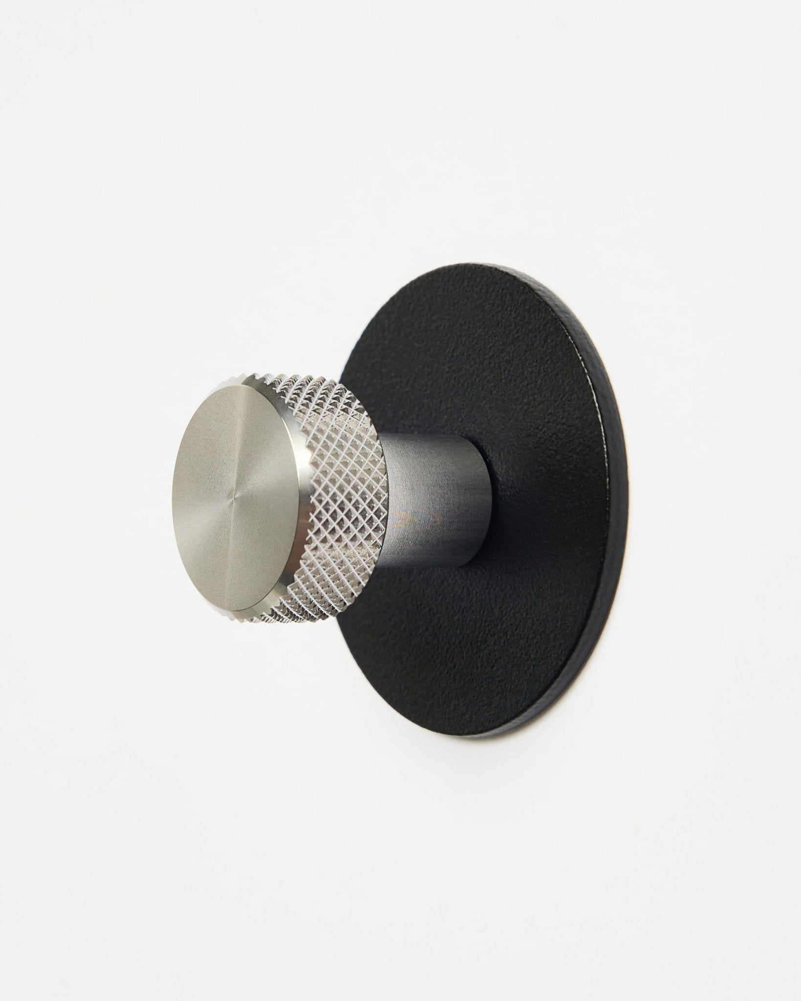 WoodUpp Norr | Coat Hook X1 i sort og rustfrit stål installeret på en almindelig hvid væg, designet som tilbehør til CREATE-kollektionen til Akupanel-systemer.