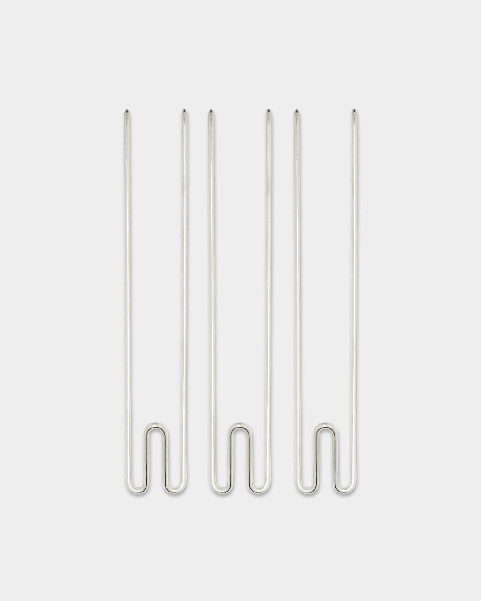 Tre Alva Wire Hook / BM1-accessories fra WoodUpp, lange kroge i rustfrit steel arrangeret lodret på en enkel hvid baggrund.