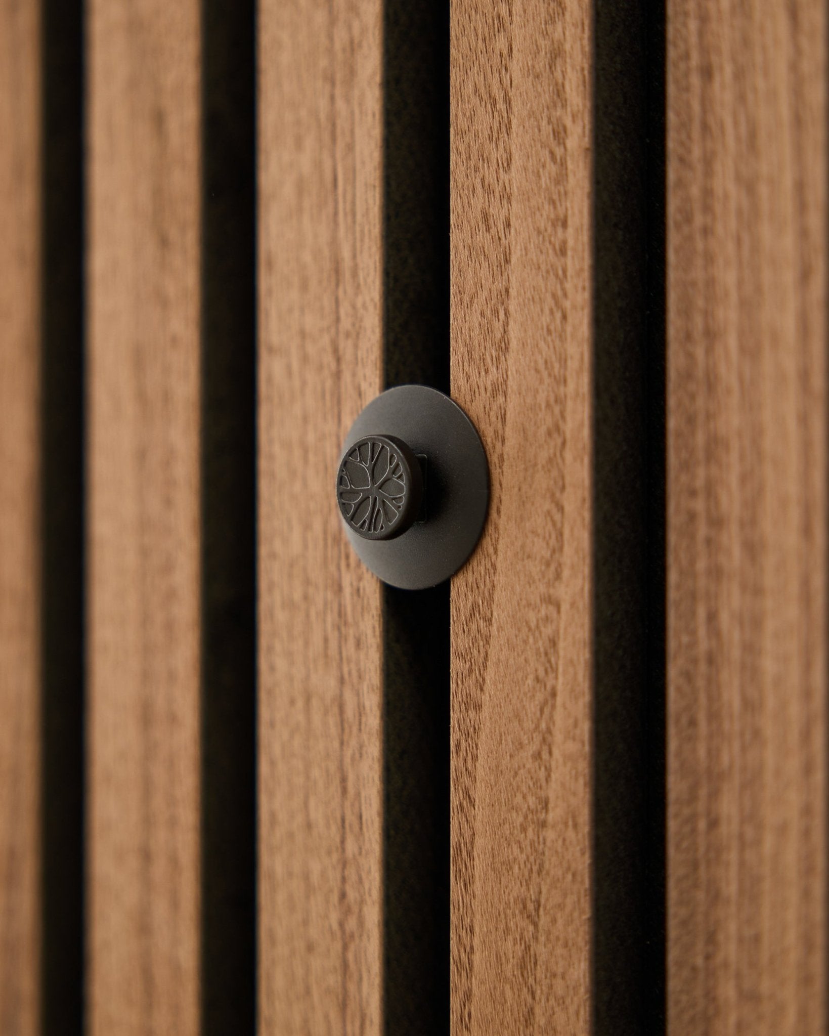 Nærbillede af en rund black-knop fra WoodUpp Dupps Original-sættet, monteret på en moderne vertical Akupanel akustisk trælamelvæg.