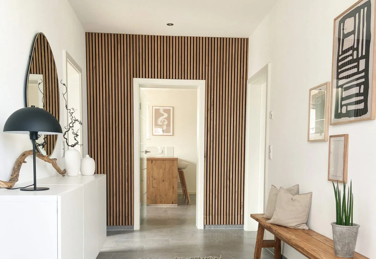 En moderne gang med en akustisk accentvæg af nordiske Akupanel-trælameller, hvide vægge, en polstret bænk og minimalistisk indretning.
