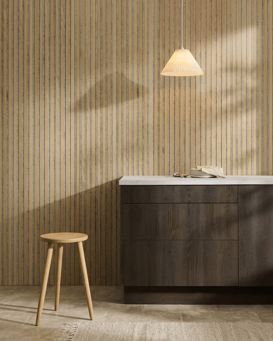 Minimalistisk nordisk interiør med et WoodUpp Akupanel Akustikpanel i Classic Oak med Grey filt, kombineret med en træskammel, et mørkt skab og en hvid bordplade.