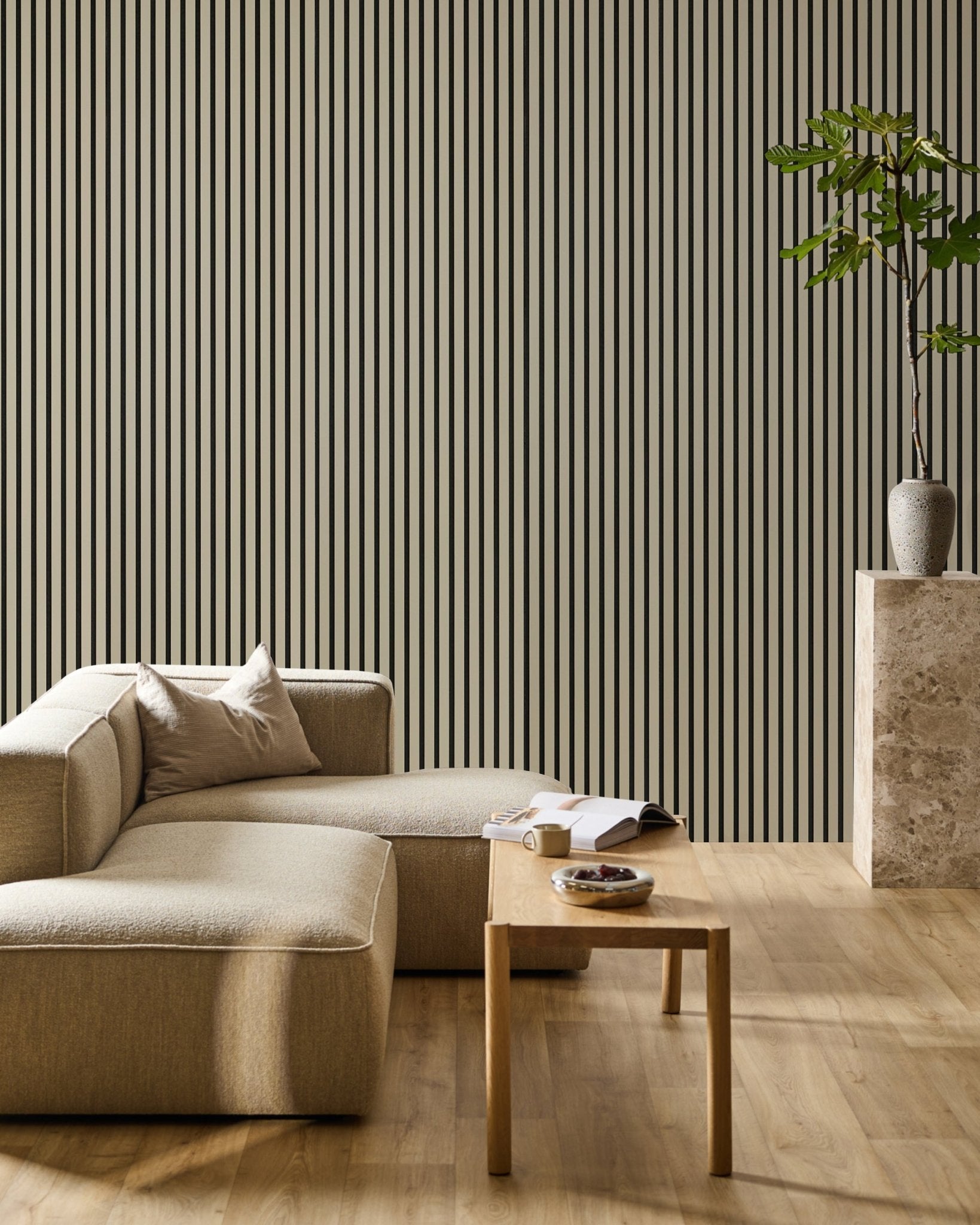 Minimalist living room featuring a beige sectional, wooden table with an open book, potted plant, and a WoodUpp Hue Akupanel Stone acoustic slatwall panel.
