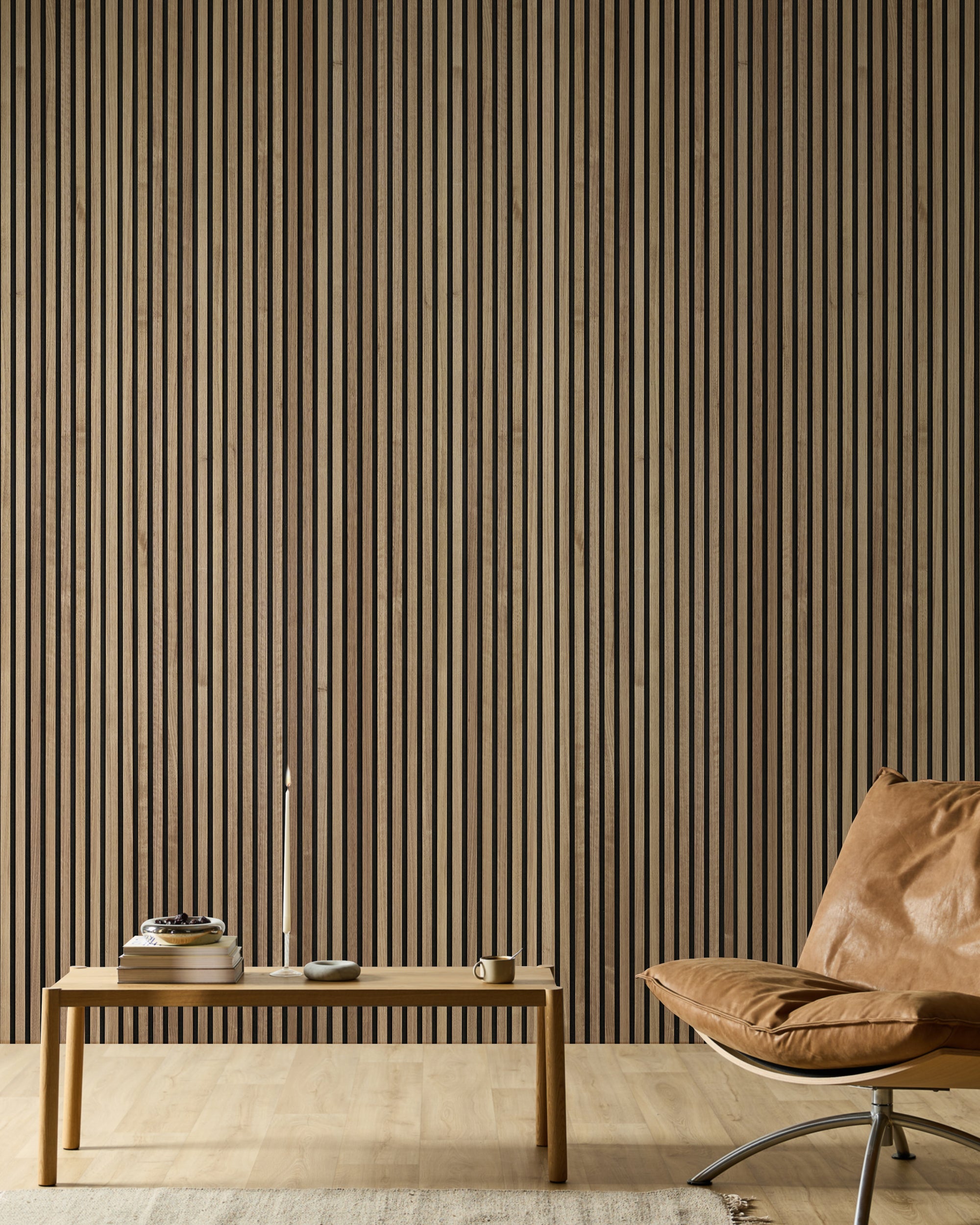Minimalistisk rum med en læderstol, en træbænk, bøger, et stearinlys og en moderne Akupanel akustisk lameltræ-accentvæg i neutrale toner.