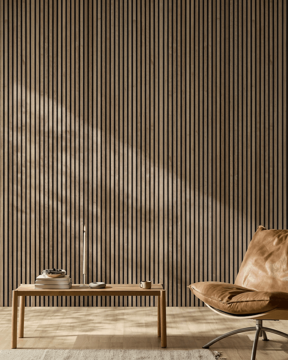 Minimalistisk nordisk rum med WoodUpp Akupanel akustikpanel i valnød, en lys tan læderstol og et sofabord i træ med bøger og et stearinlys.