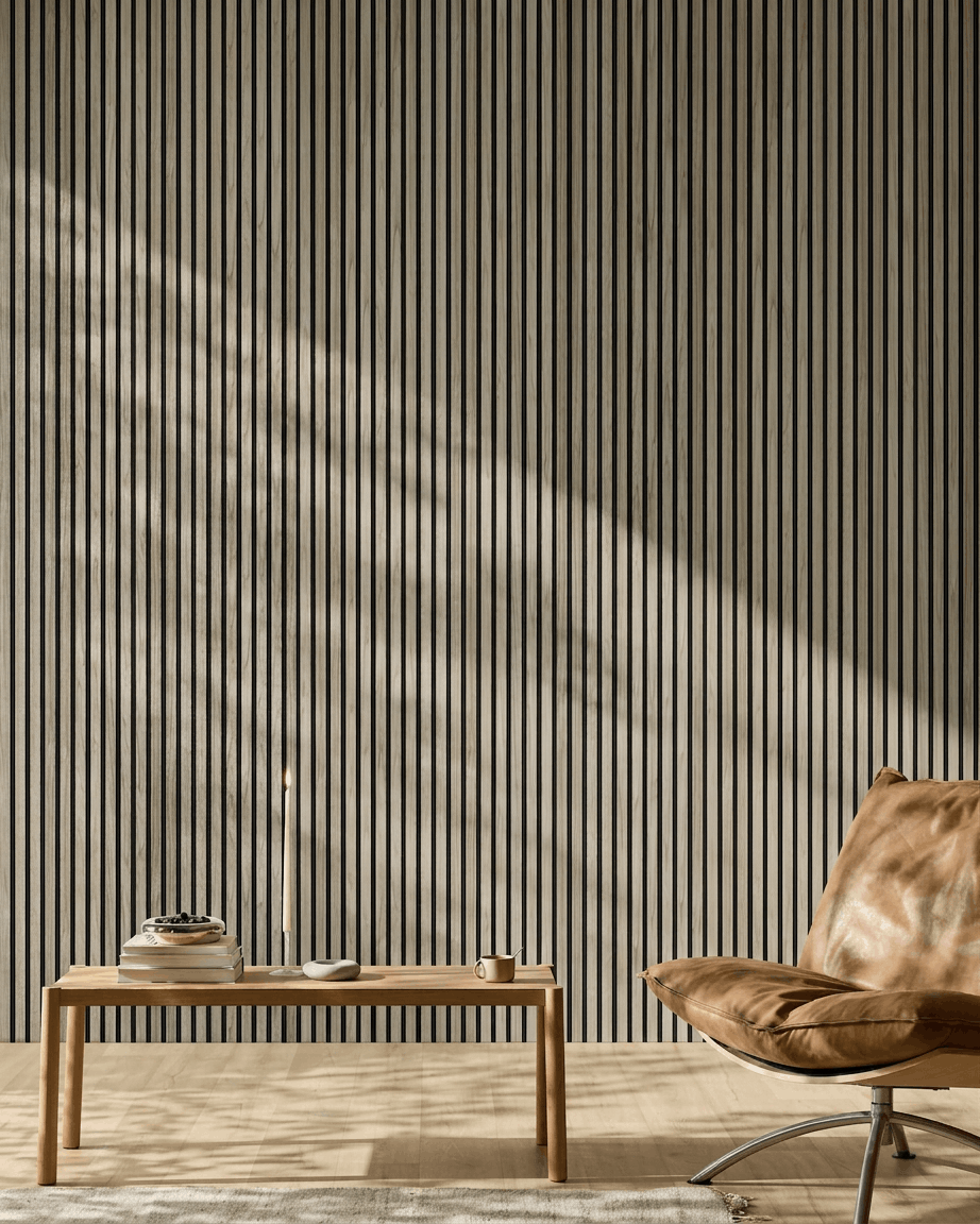 Minimalistisk rum med et 240x60 cm WoodUpp Akupanel i Weathered Oak med black filt, træbænk, bøger, stearinlys, kop og lysebrun læderstol.