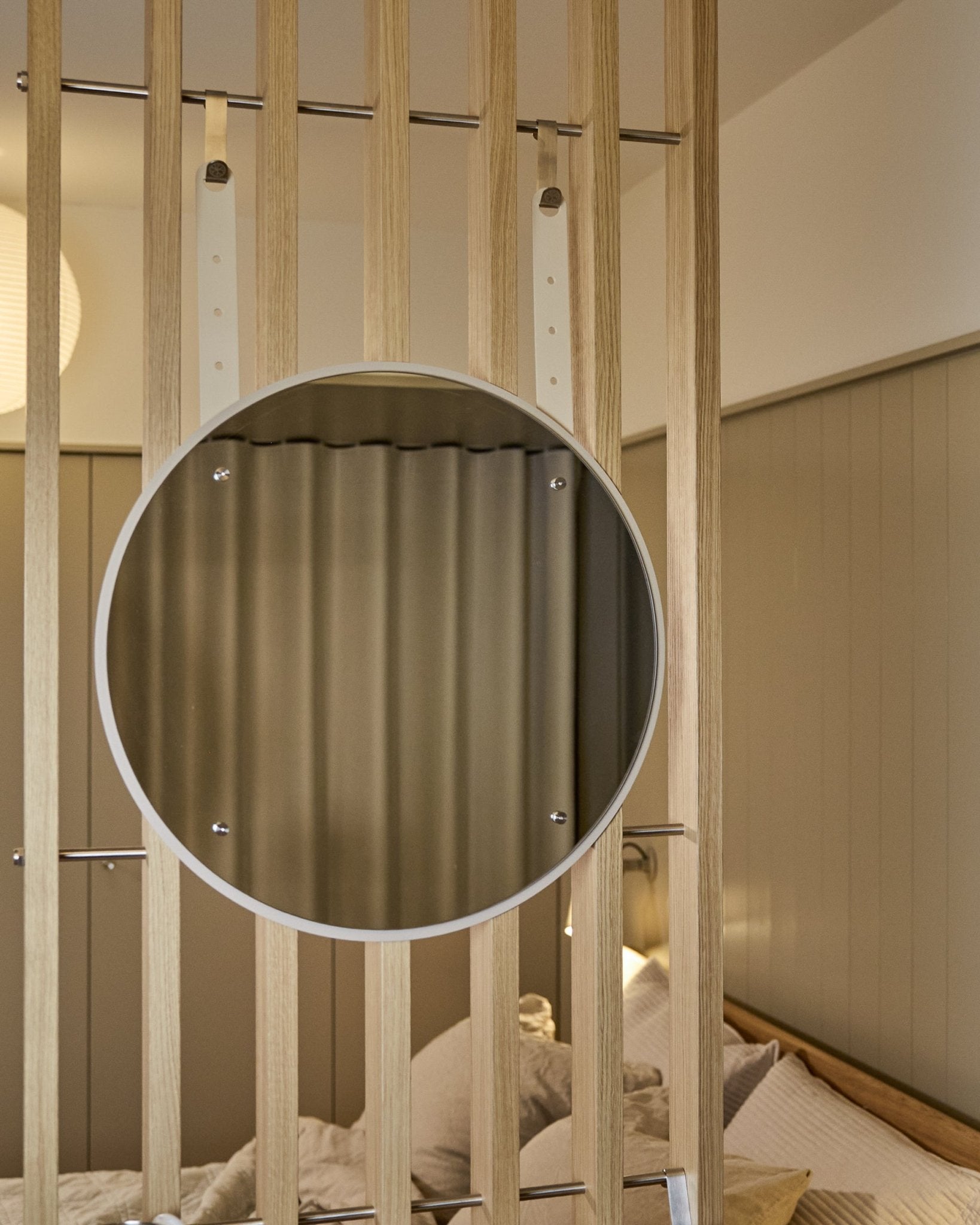 Round, height-adjustable Vala BM1 mirror by WoodUpp, 54 cm diameter, mounted on vertical acoustic wood slat panel with soft neutral lighting.