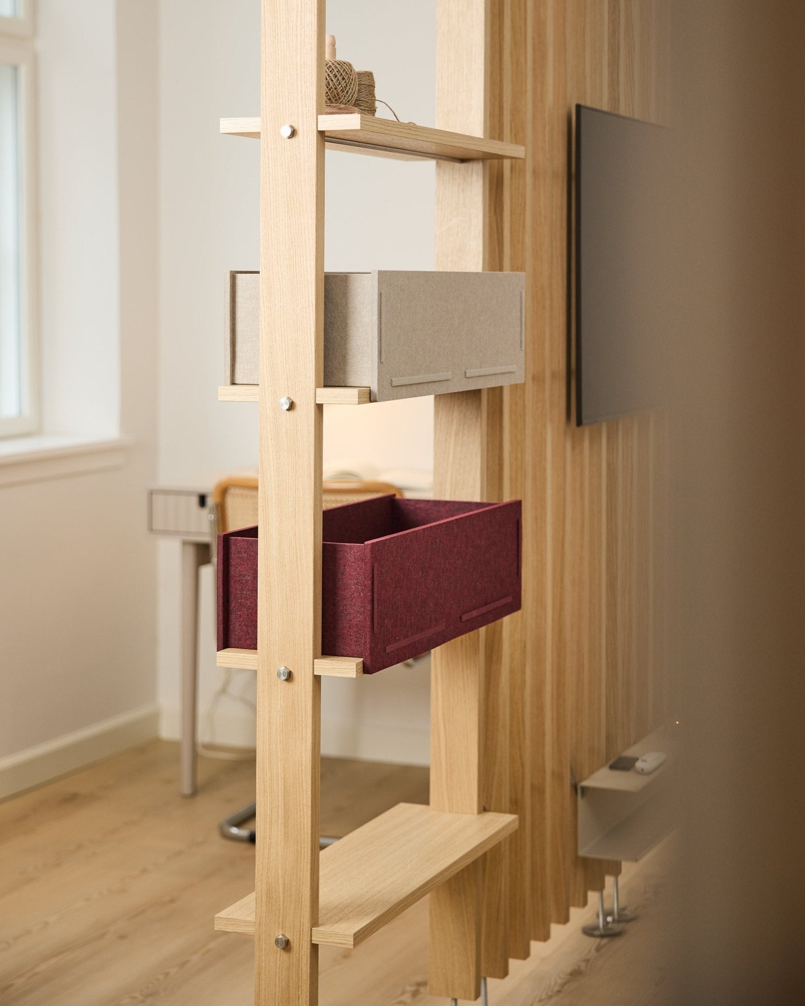 A WoodUpp shelf displays a beige storage box and an ox red Vigg Felt Box / BM2 in a bright, minimalist Nordic room with acoustic wood detailing.