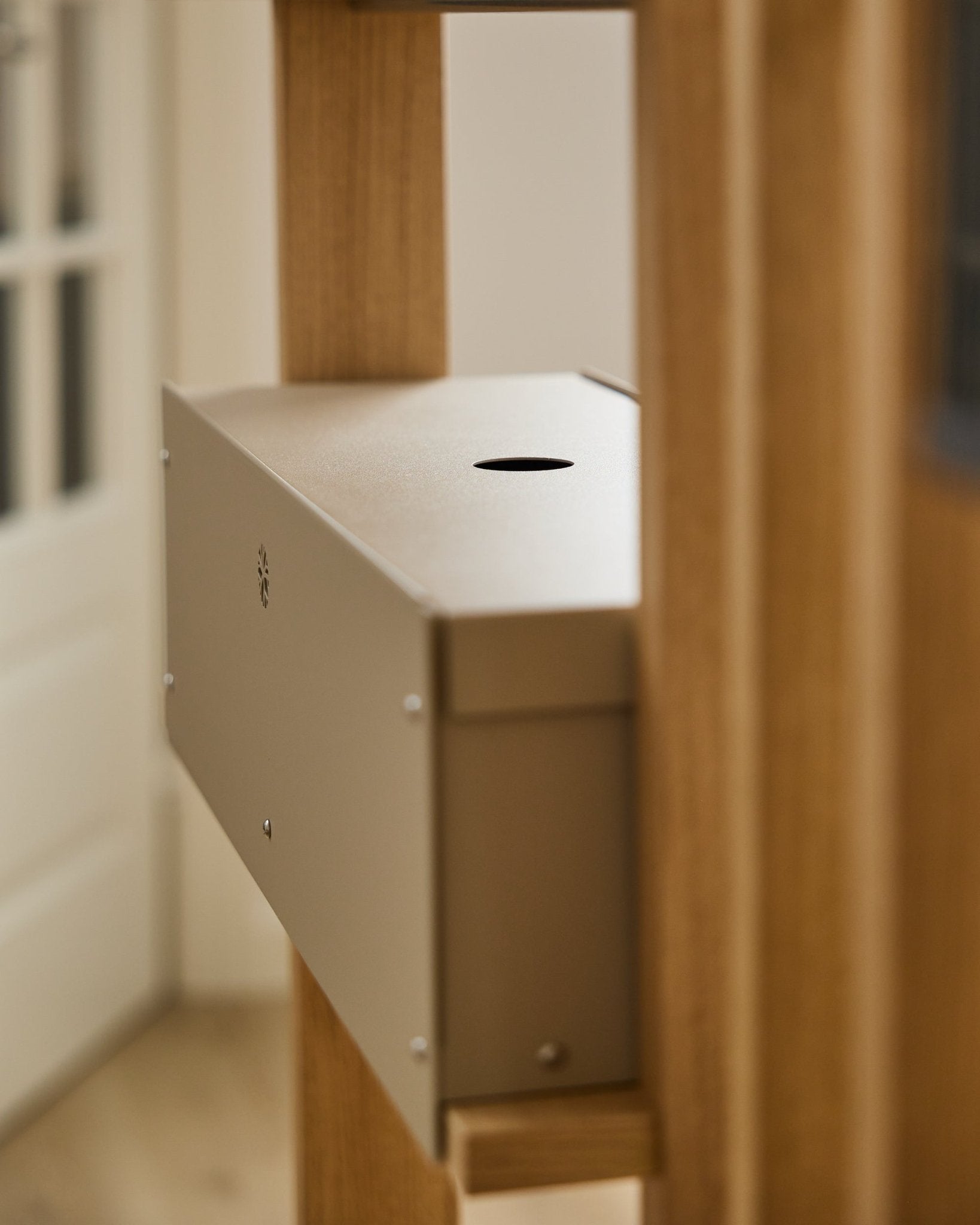 Nell | Metal Box / BM2, Beige fra WoodUpp er et pulverlakeret steel-tilbehør fra CREATE kollektion, placeret mellem akustiske træpaneler nær en hvid dør.